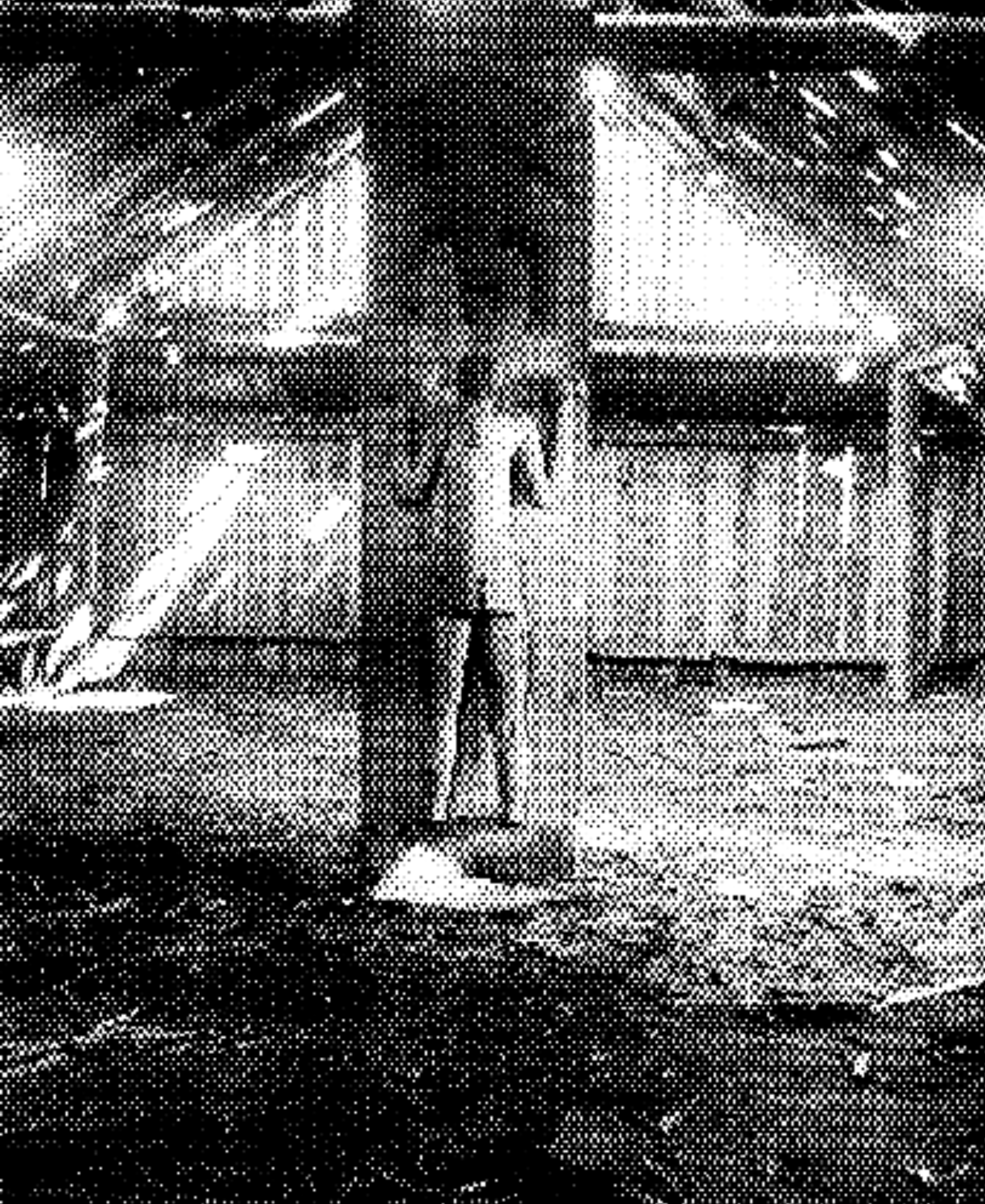 A person standing next to a sports car on a street at night, with a building and lit windows in the background.