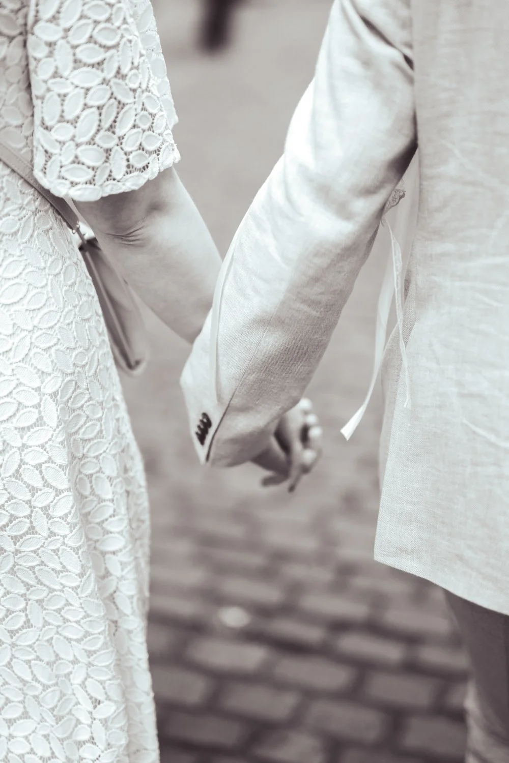 Nahaufnahme eines Paares, das sich hält, in formeller Kleidung, vermutlich bei einer Hochzeit.