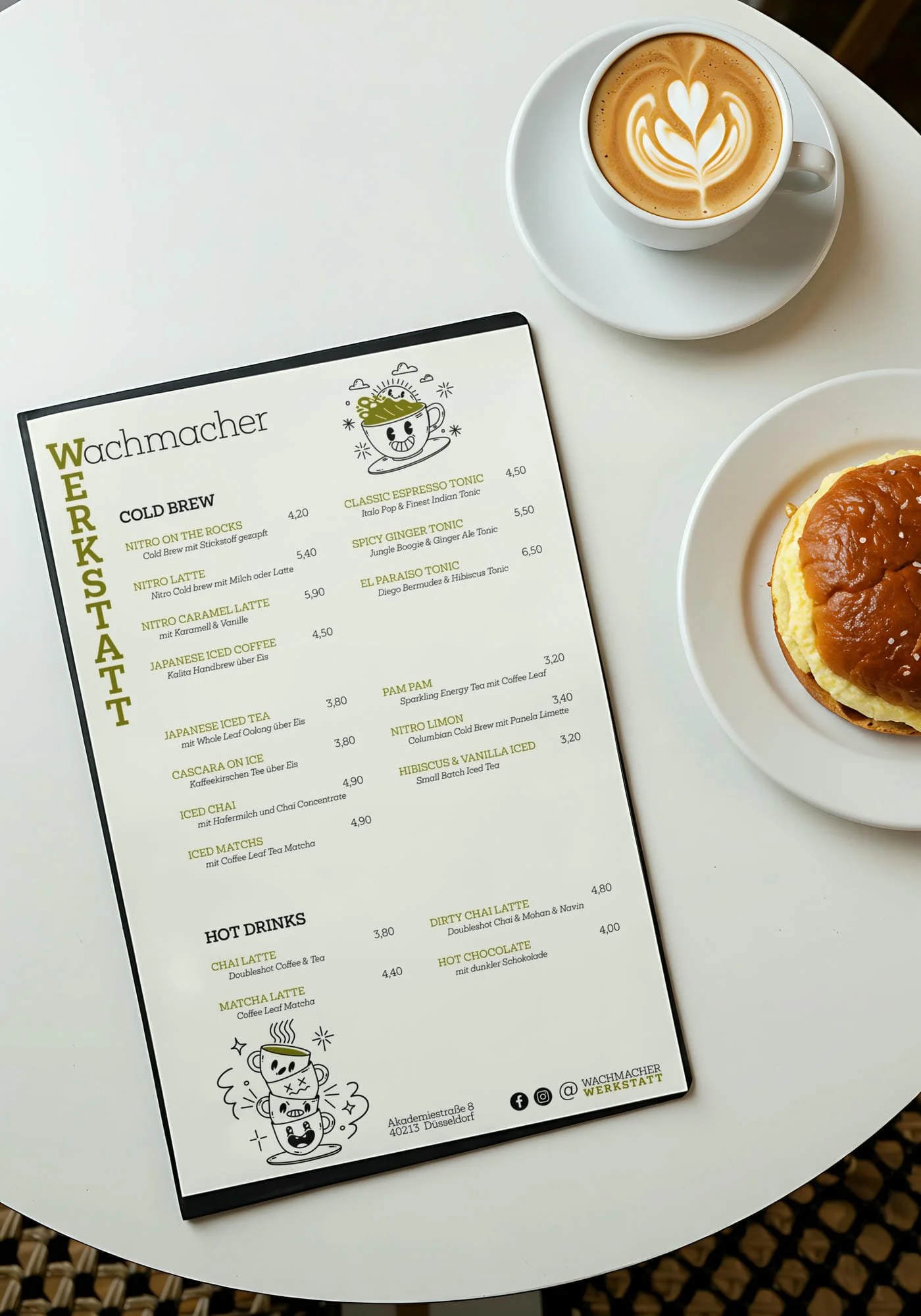 Getränkekarte für Kaffee und Tees, eine Tasse Latte mit Latte Art und eine Kekstorte auf weißen Tellern, eine Tasse Kaffee mit Herzdesign, auf weißem Tisch.