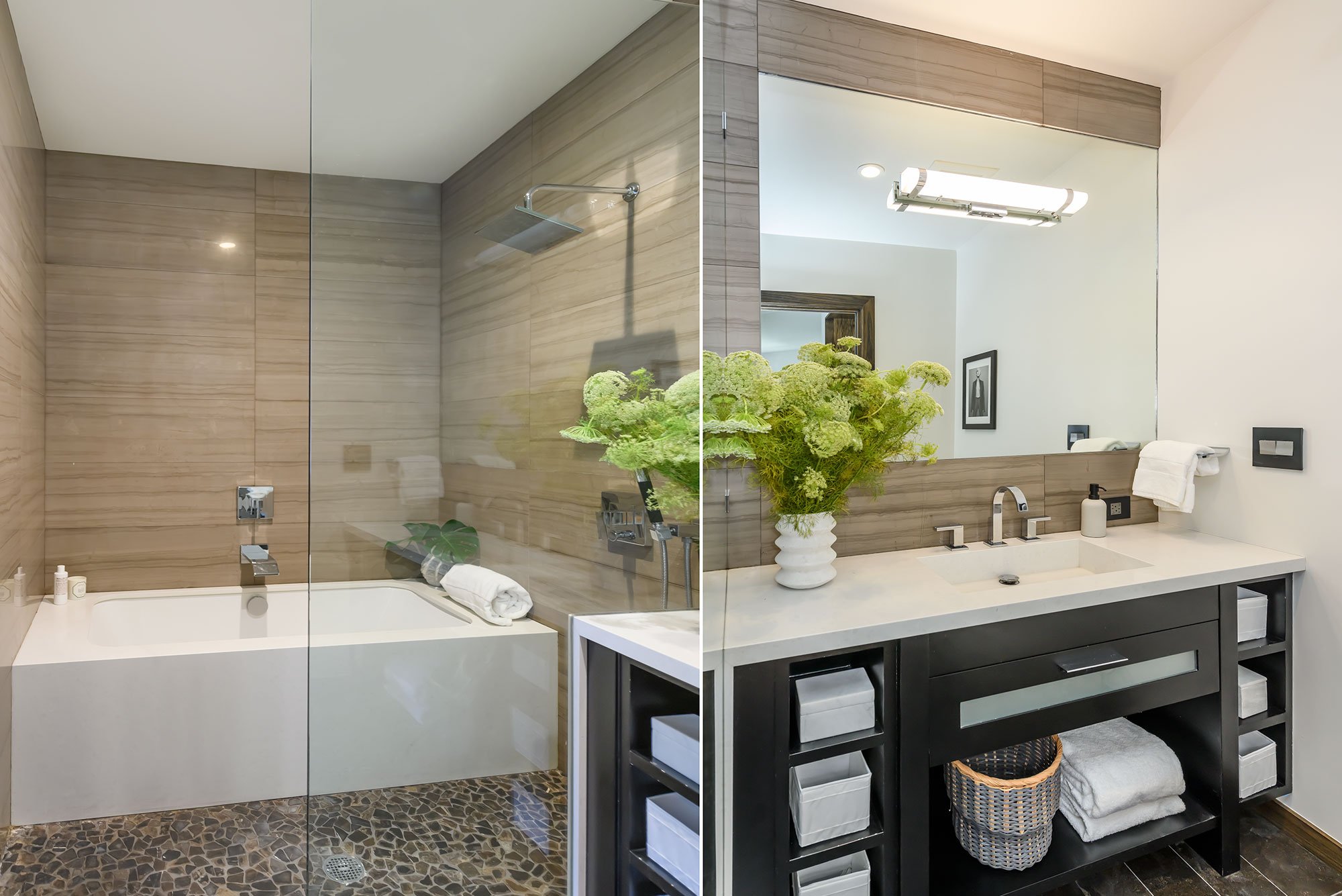 Split view of a bathroom with a walk-in shower on the left featuring beige wall tiles, a rain showerhead, and a bathtub; on the right, a modern sink area with a large mirror, a potted green plant, a framed black-and-white picture, and black cabinetry