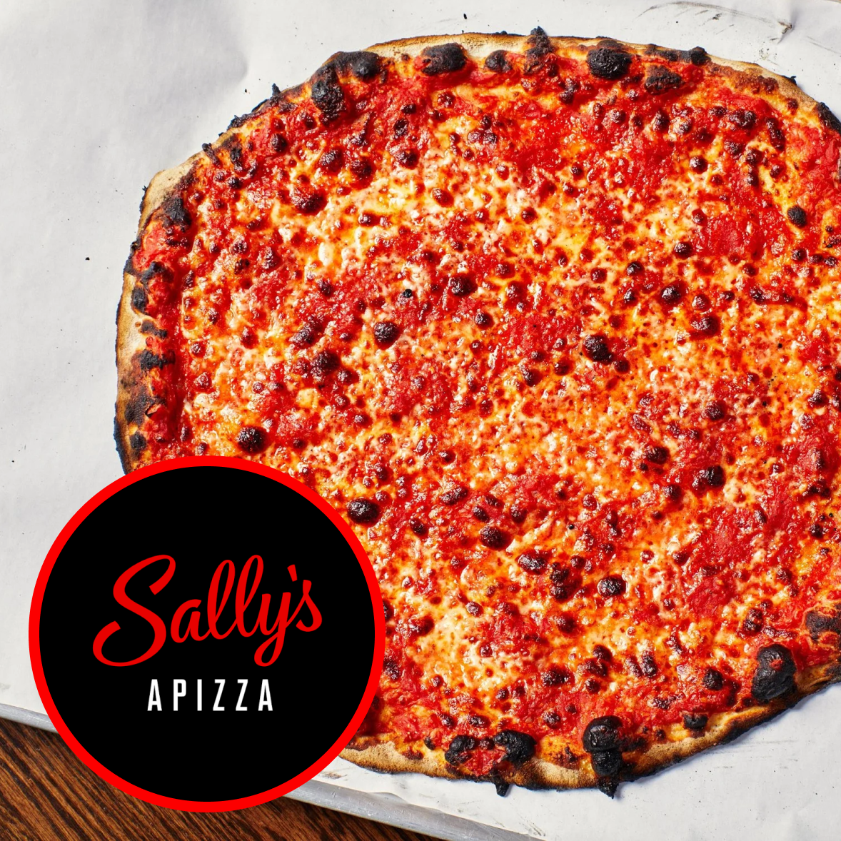 A cheese pizza with a slightly burned crust and a red sauce, topped with melted cheese and some charred spots. A black and red logo in the lower-left corner reads 'Sally's Pizza'.
