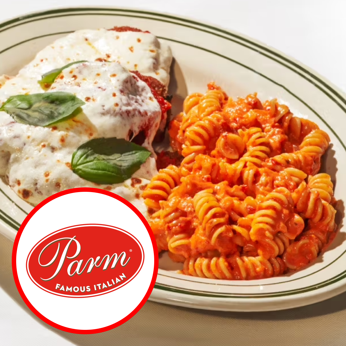 Plate of rotini pasta with marinara sauce and chicken topped with melted cheese and basil leaves.