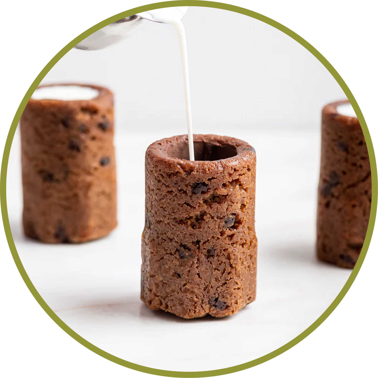Chocolate chip cookie-shaped edible straw with milk being poured into it.