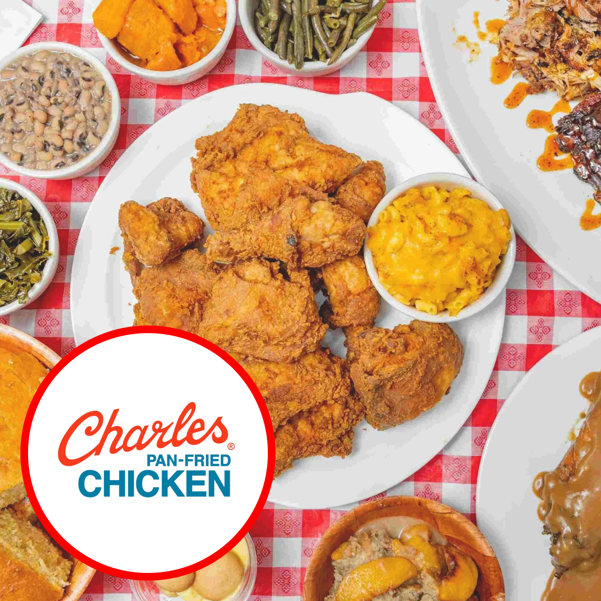 Fried chicken with sides of macaroni and cheese, green beans, baked sweet potatoes, and baked beans on a checkered tablecloth.