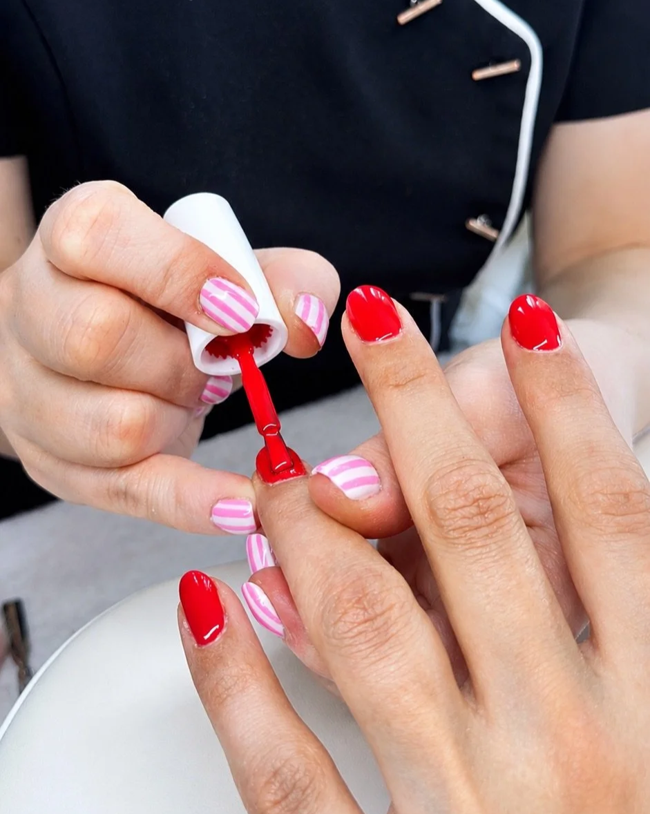 Julia Wijnen die rode nagellak aanbrengt op nagels van een klant.