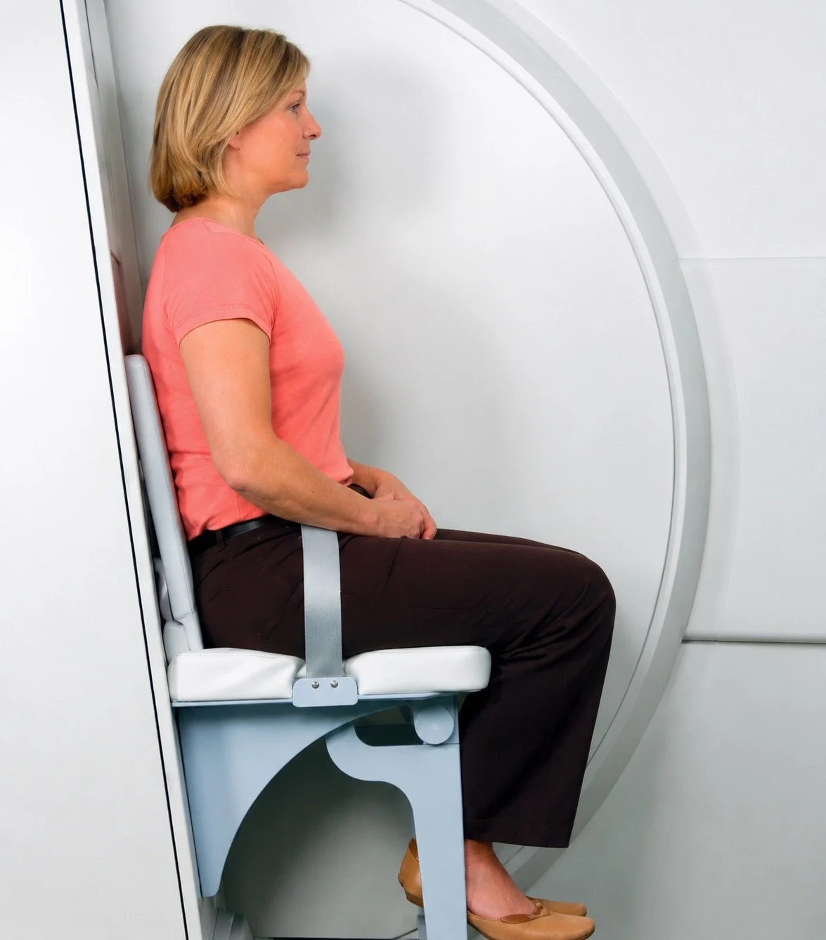 Woman sitting in a medical MRI machine in a hospital or medical facility.