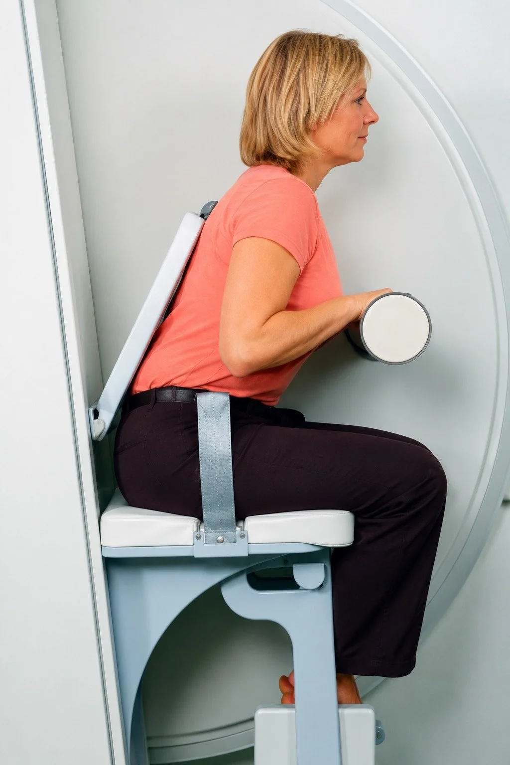 Woman sitting upright in a medical imaging machine, preparing for a scan.