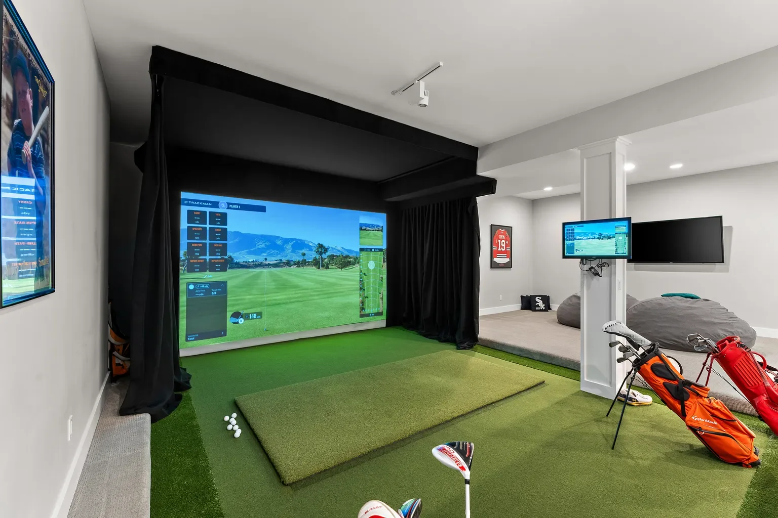 This Sand Creek home's finished basement has both a lounge space and an indoor golf simulator bay, which comes with a large projection screen, hitting mat, and artificial turf green.