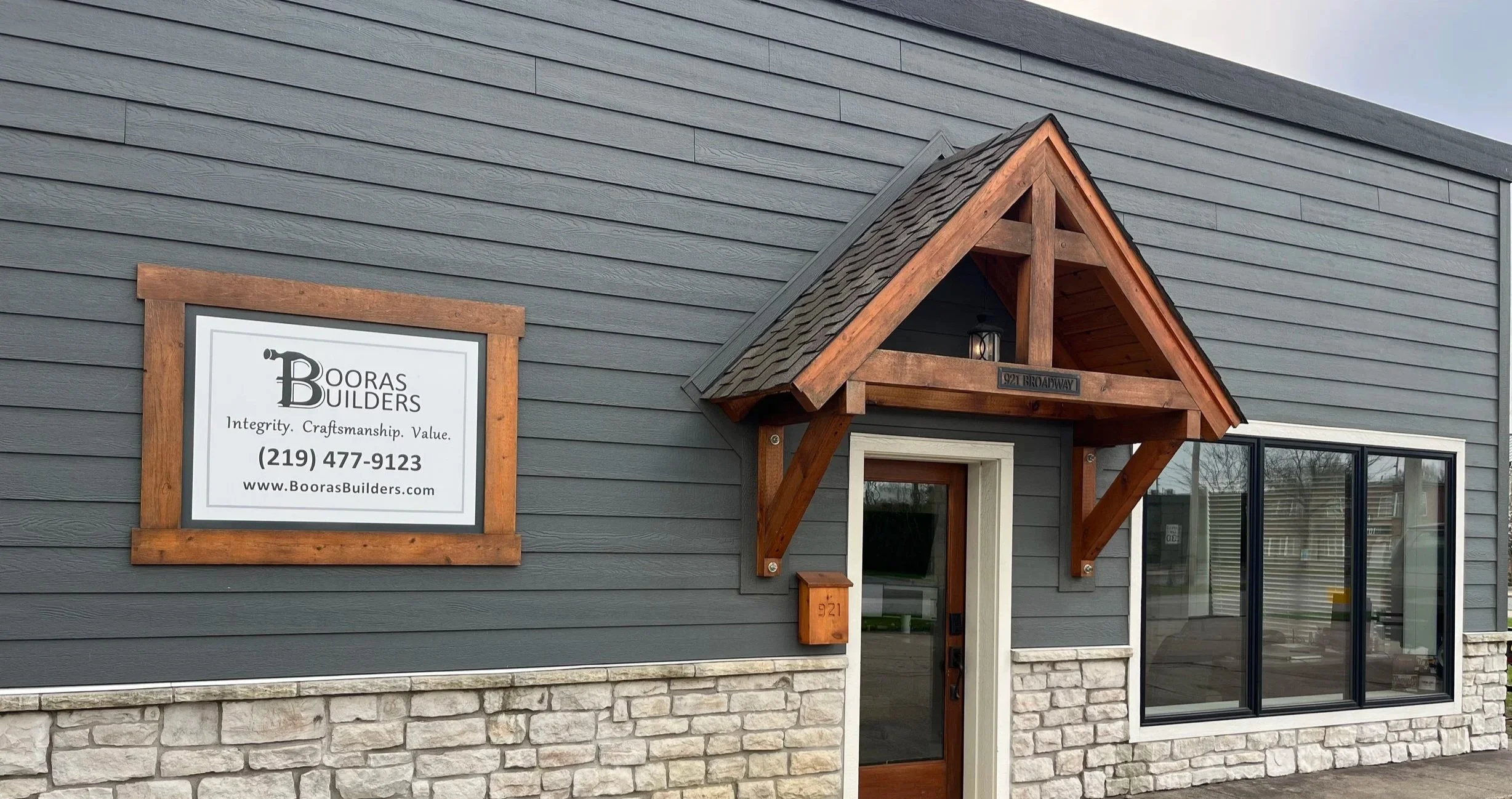 The Booras Builders office in downtown Chesterton was customly designed and built by Booras Builders themselves. Its exterior is half dark gray siding and half stone. A gabled roof juts out over the entry door. The windows have black and white trim.