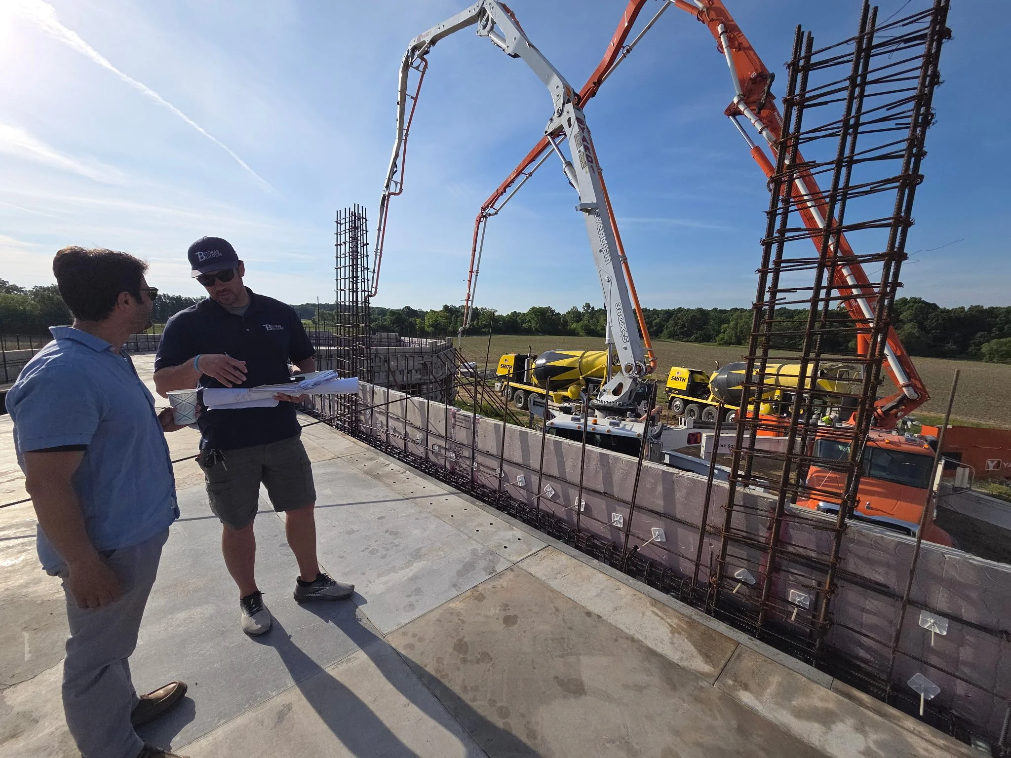 A Booras Builders Project Manager discusses a project with a client on an active jobsite in Chesterton, Porter County. Cranes are being used in the foundation's construction.