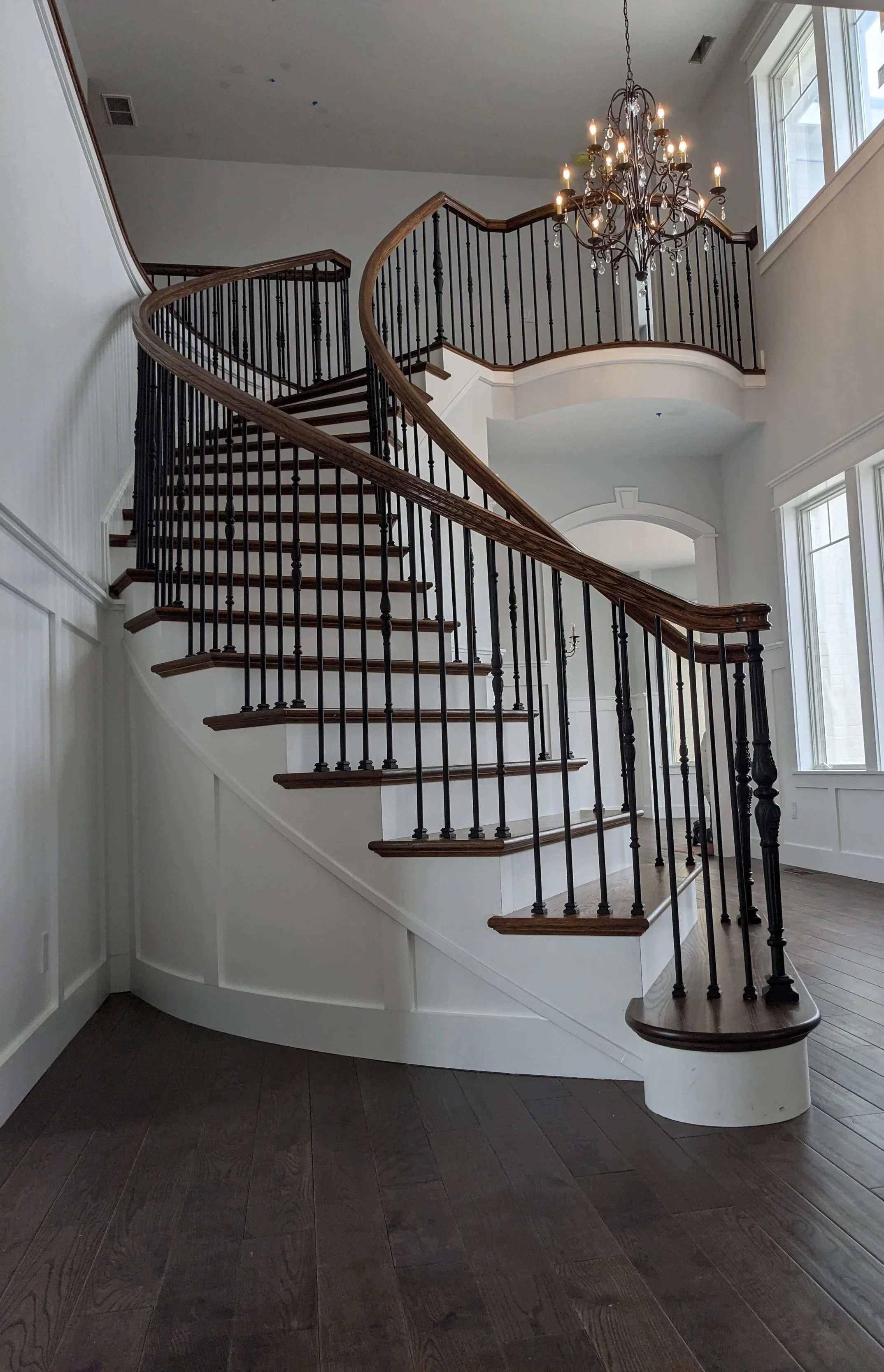 A custom-crafted curving staircase with intricate railings and a luxury light fixture in a Booras Builders custom-built home located in Chesterton, Porter County.