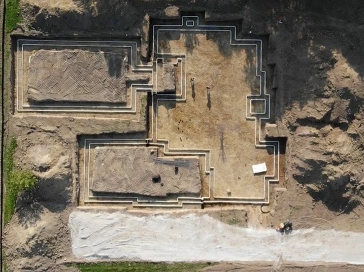 These foundation outlines, as showcased by an aerial drone view, mark the initial ground-up phase of a custom residential construction site being built by Booras Builders. Near the foundation outlines are surrounding earthwork and a gravel driveway.