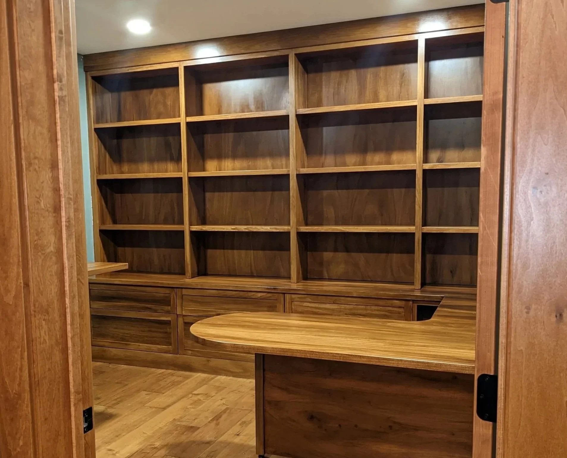 A personalized home office designed and built by Booras Builders for a home in Chesterton, featuring a floor-to-ceiling built-in bookcase wall, integrated storage drawers, and a matching wrap-around executive desk.