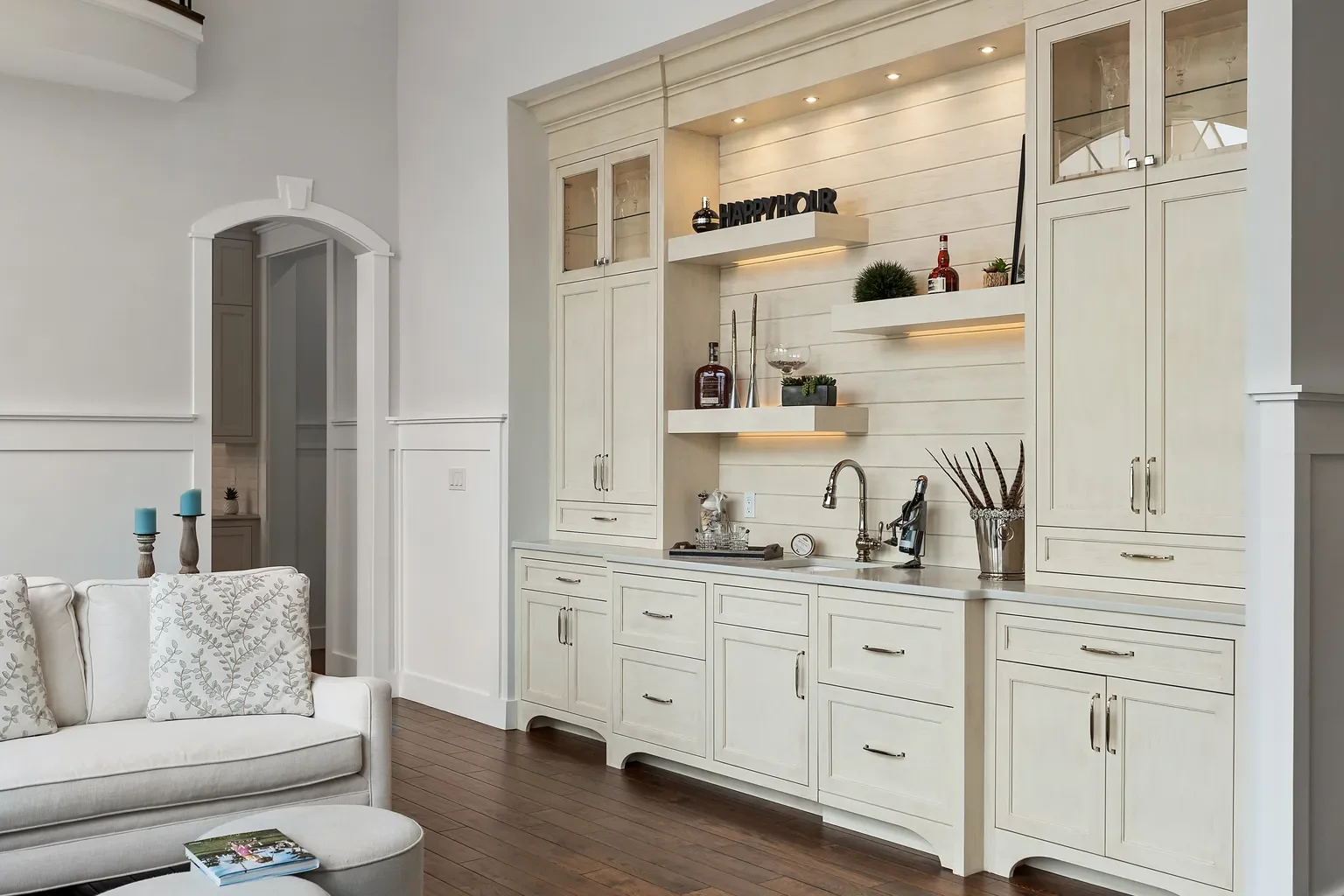 Built-in wet-bar cabinetry featuring an integrated shiplap backsplash, under-cabinet lighting, and floating display shelves highlights a custom detail of a home built by Booras Builders.