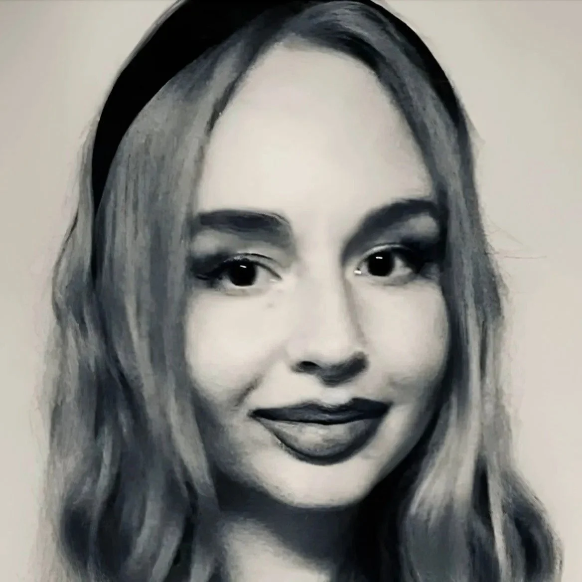 A black and white portrait of a woman with long wavy hair, smiling, with makeup and dark lipstick.