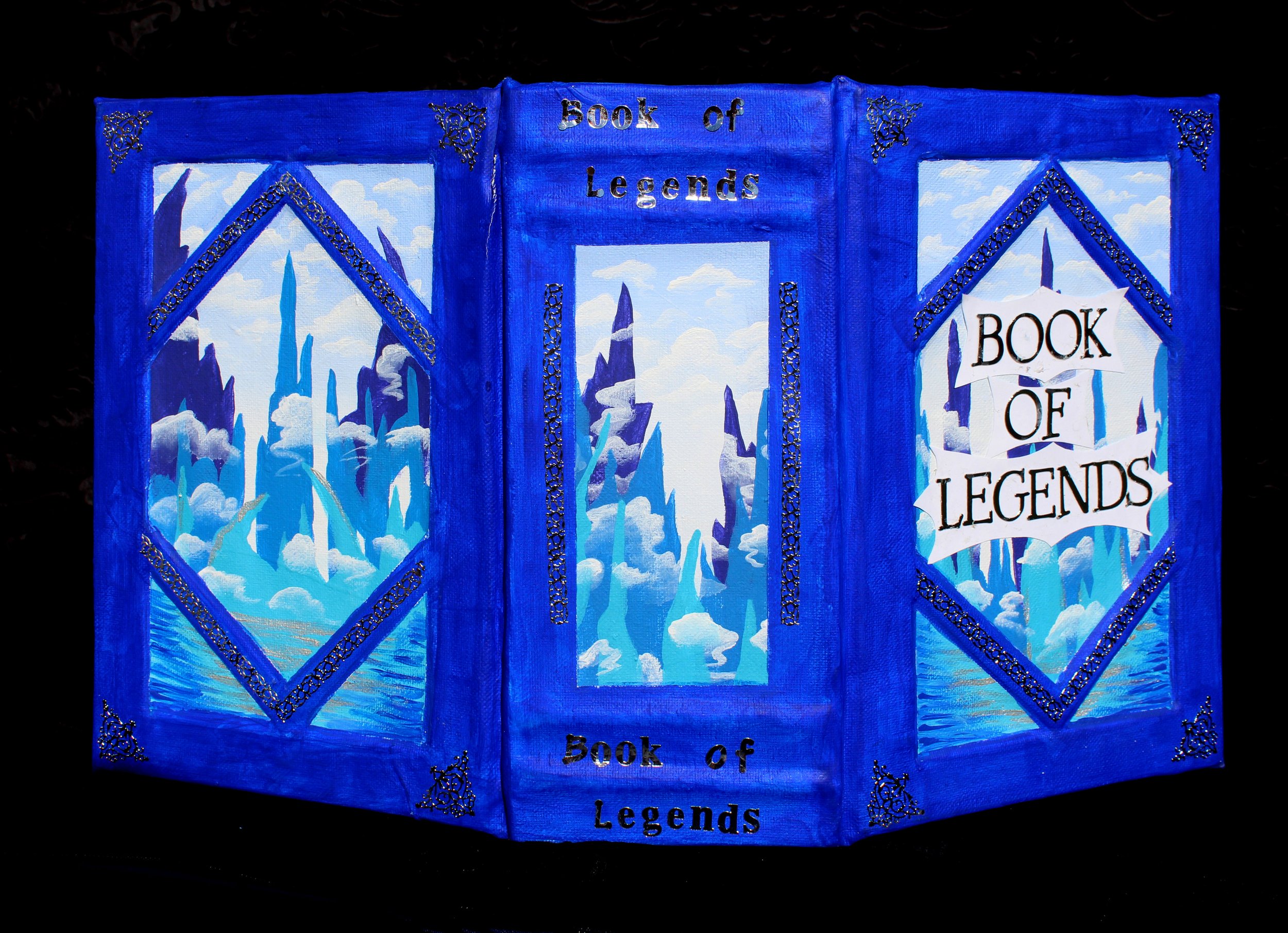 Painting of a blue book cover with ice towers and clouds, titled 'Book of Legends'.