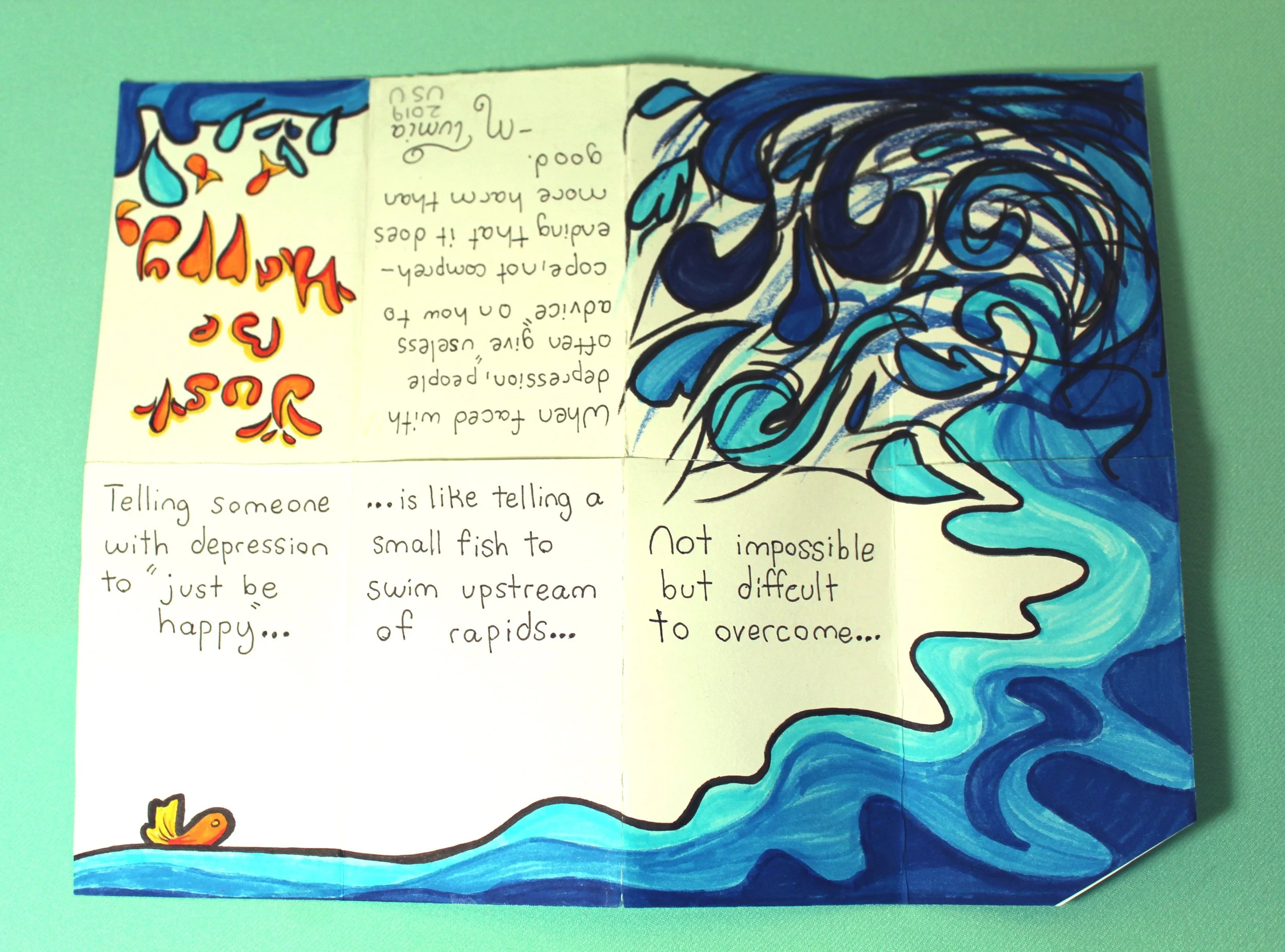 A colorful homemade booklet with handwritten notes and a large blue and black abstract wave design on the right side. The left side has a three-line note in red and yellow, and below that, a paragraph about telling someone a secret.