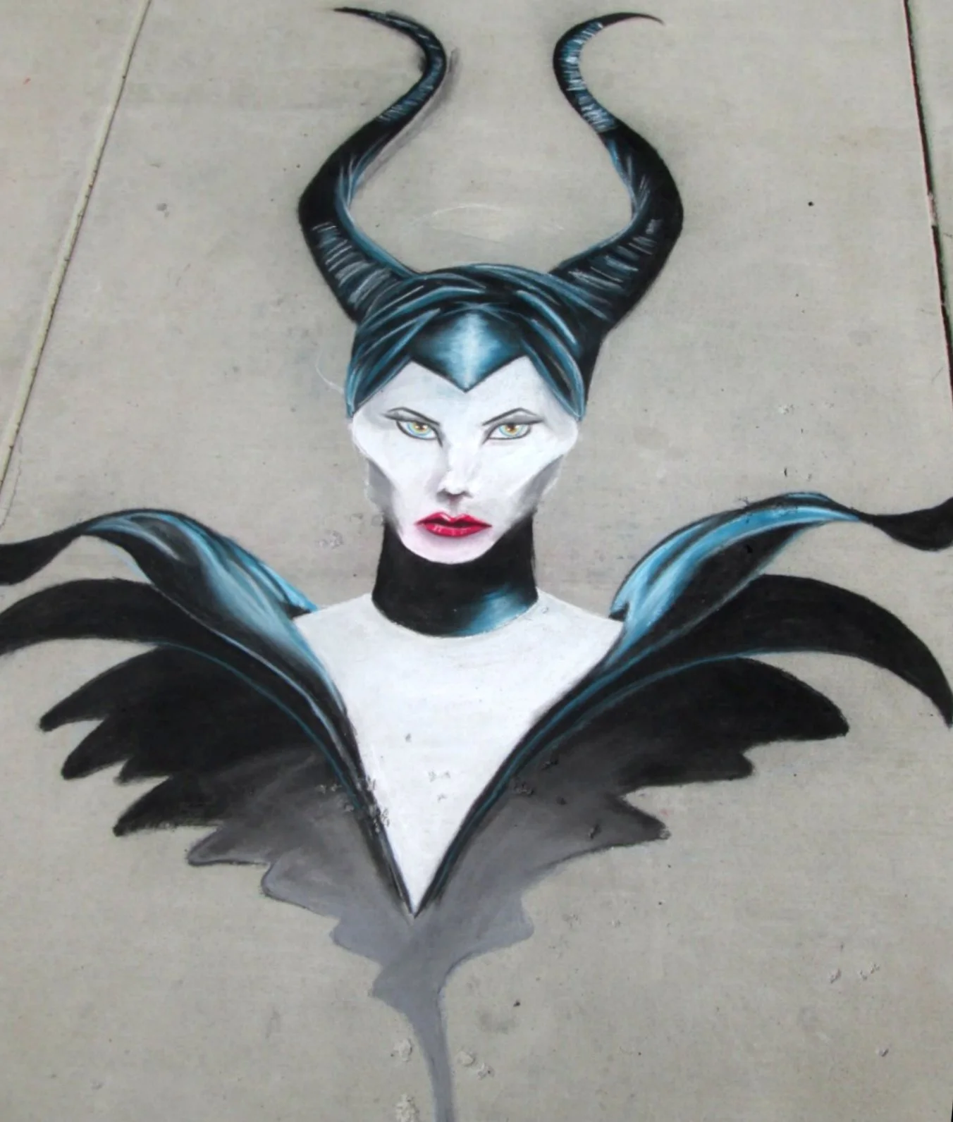 Street artwork of a woman with blue and black hair, intense eyes, red lips, and black wings, with a horned headdress extending upward.