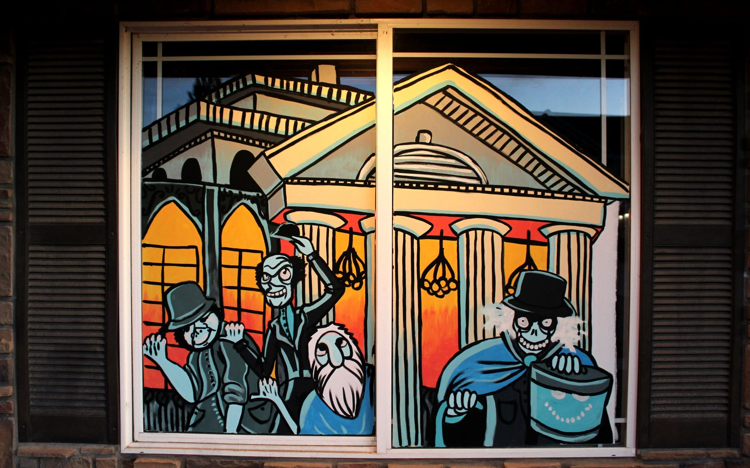 Street art mural depicting a cheerful skeleton in a blue suit and black hat, with other skeletons and a large building with domes and arches in the background.
