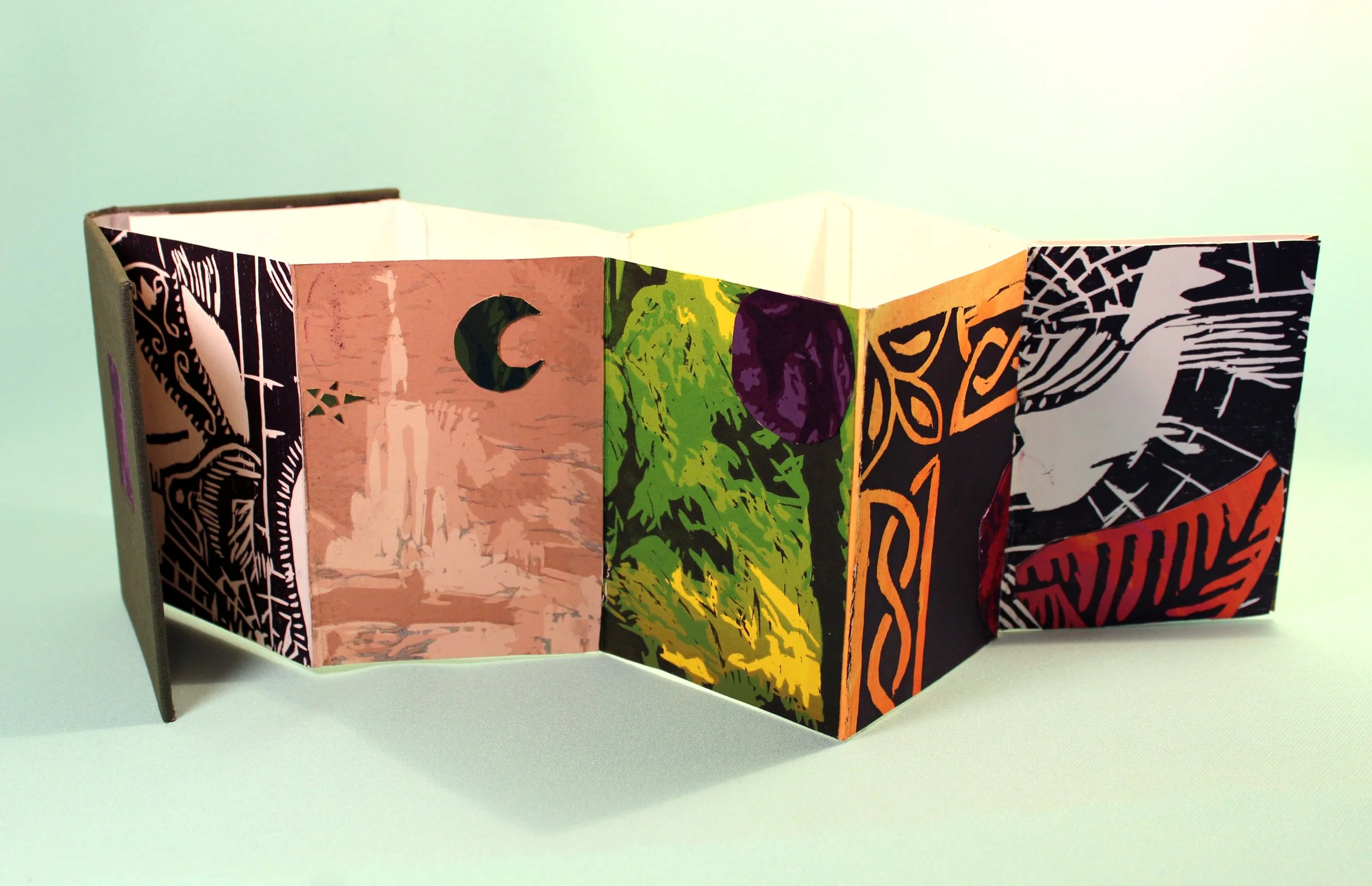 A colorful folding brochure with abstract and graphic designs on each panel, standing open against a light green background.