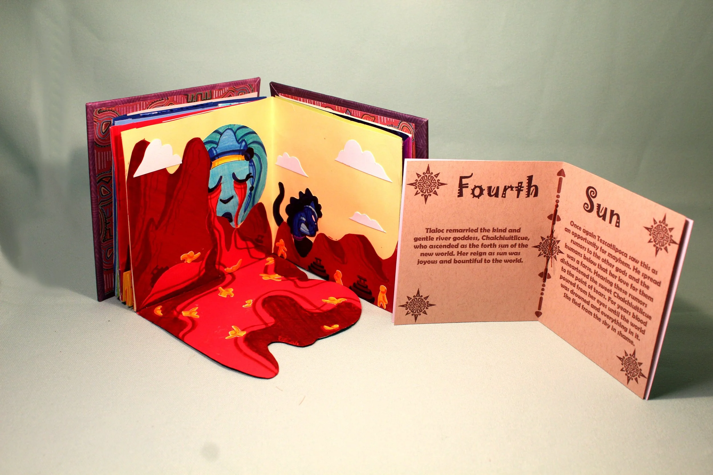 A pop-up storybook featuring colorful illustrations of a character with a blue face and red clothing, set against a desert landscape with mountains and clouds, with a pink pop-up informational card next to it.