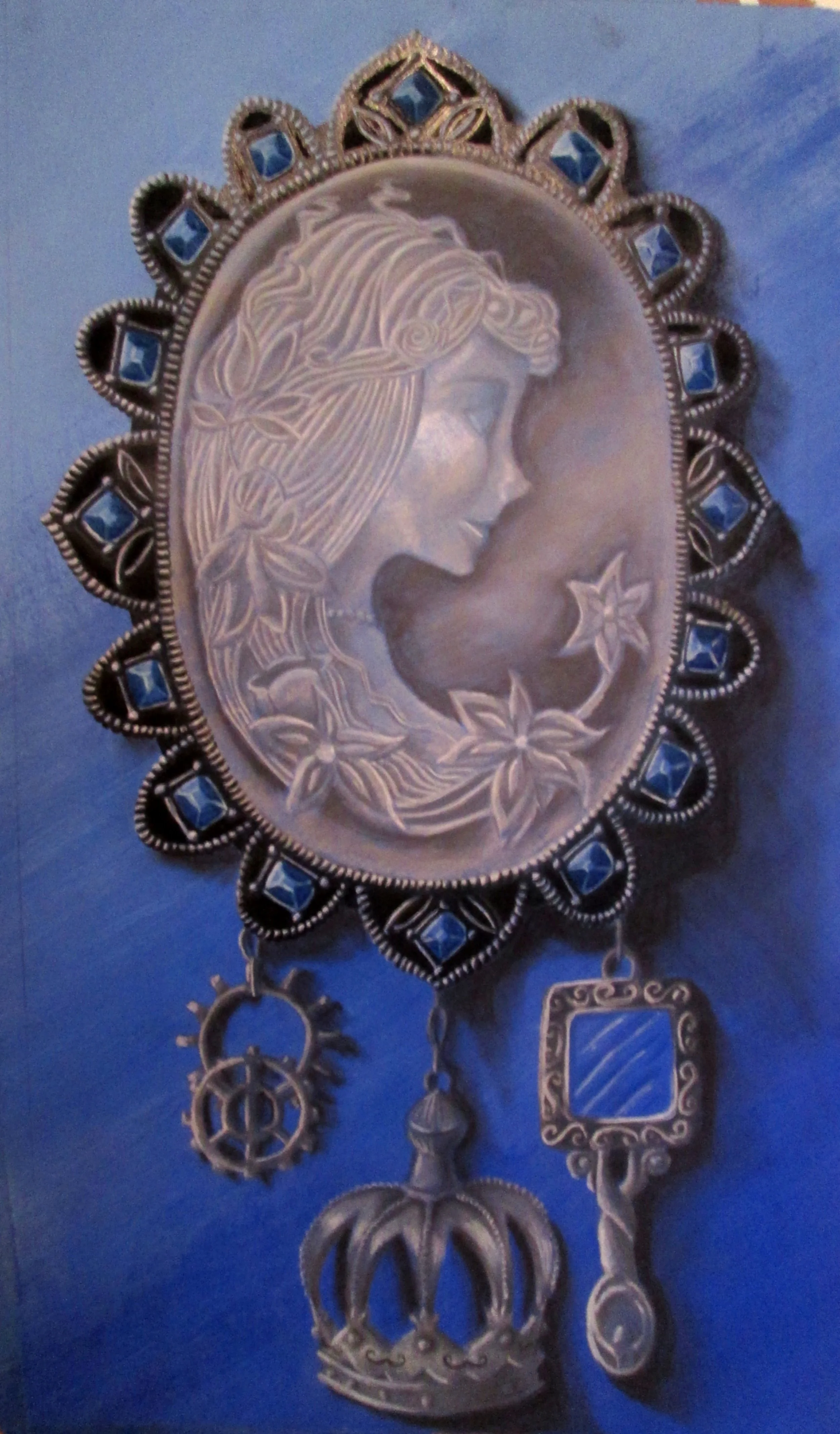 Silver pendant necklace featuring a carved profile of a woman with flowing hair, surrounded by intricate decorative elements with blue accents, hanging charms, and gears.