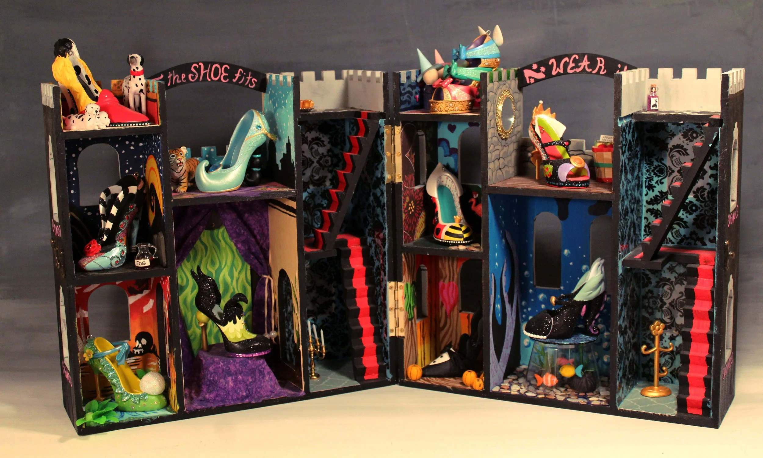 Colorful miniature dollhouse with multiple rooms filled with shoes, accessories, and decor, including a tiger figurine, black cat, and various tiny objects.