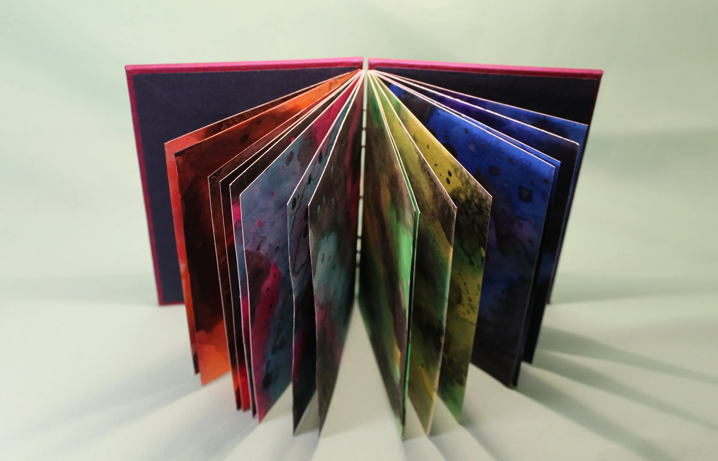 Colorful watercolor pages fanned out in a book or brochure.