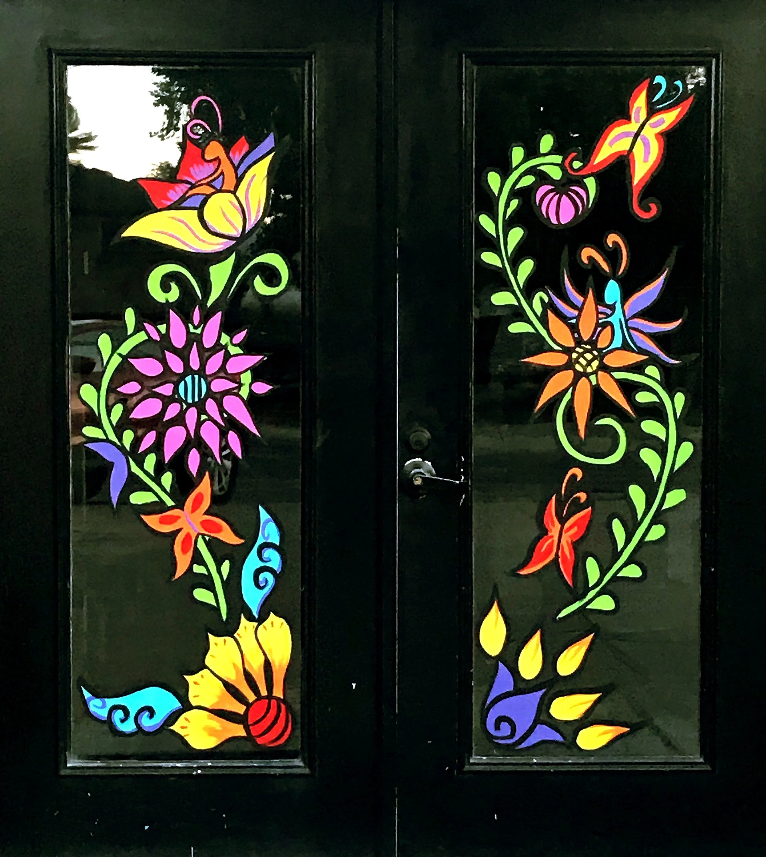 Colorful stained glass butterfly and floral designs on black background.