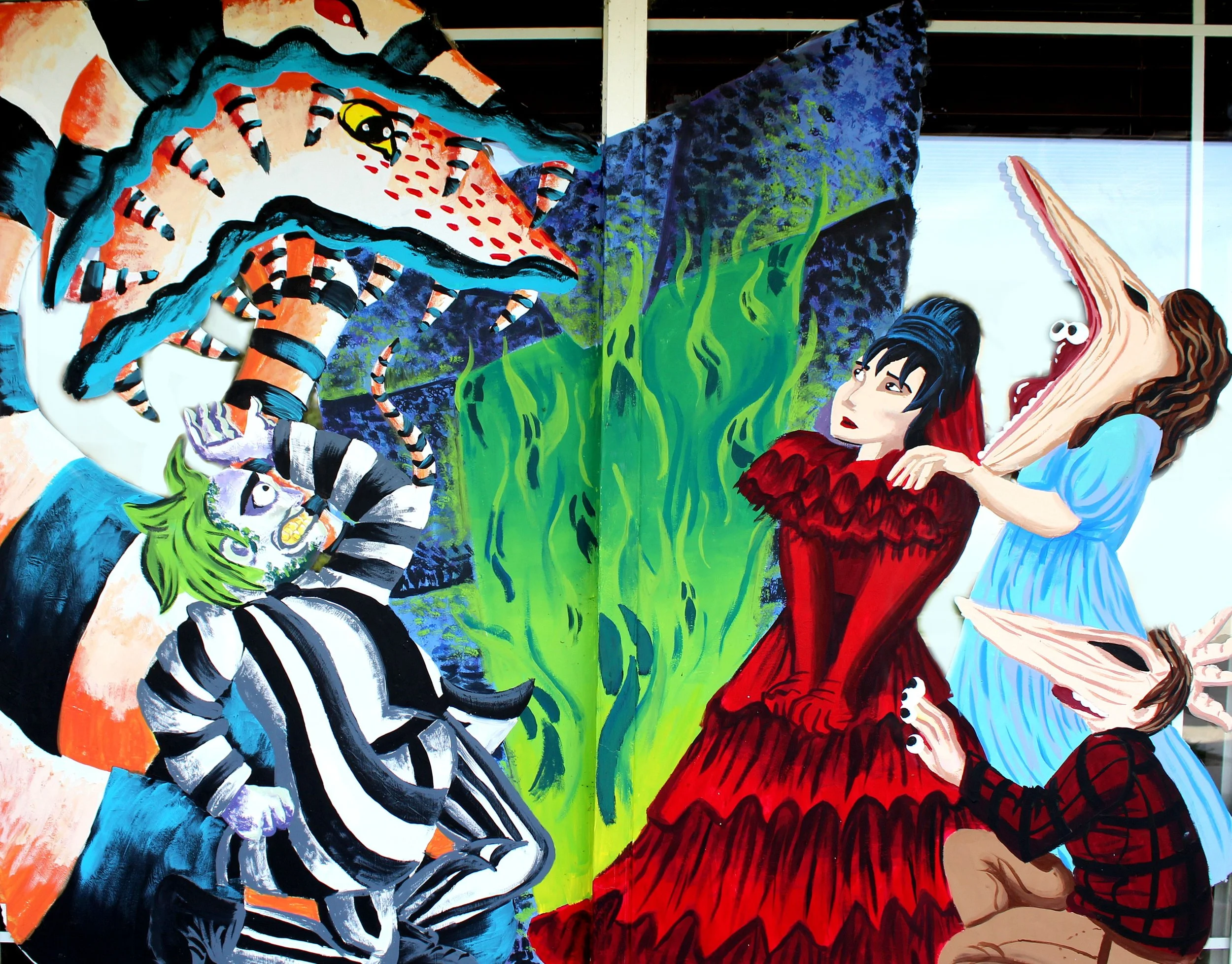 Colorful mural depicting a princess in a blue dress, a large crocodile, a zebra-striped figure, and a monster with green hair, set against a vibrant background of blue, green, and purple.