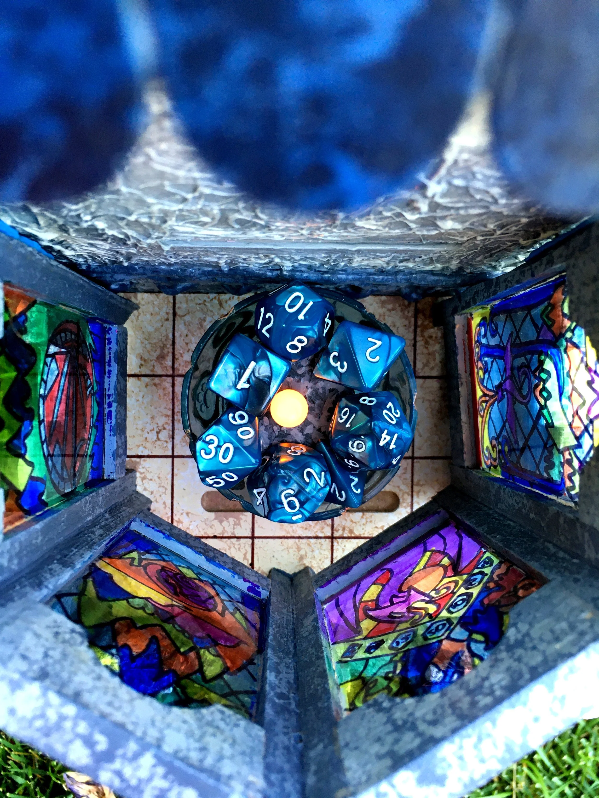 A collection of polyhedral dice with numbers face up, placed inside a container decorated with colorful, graffiti-style artwork.