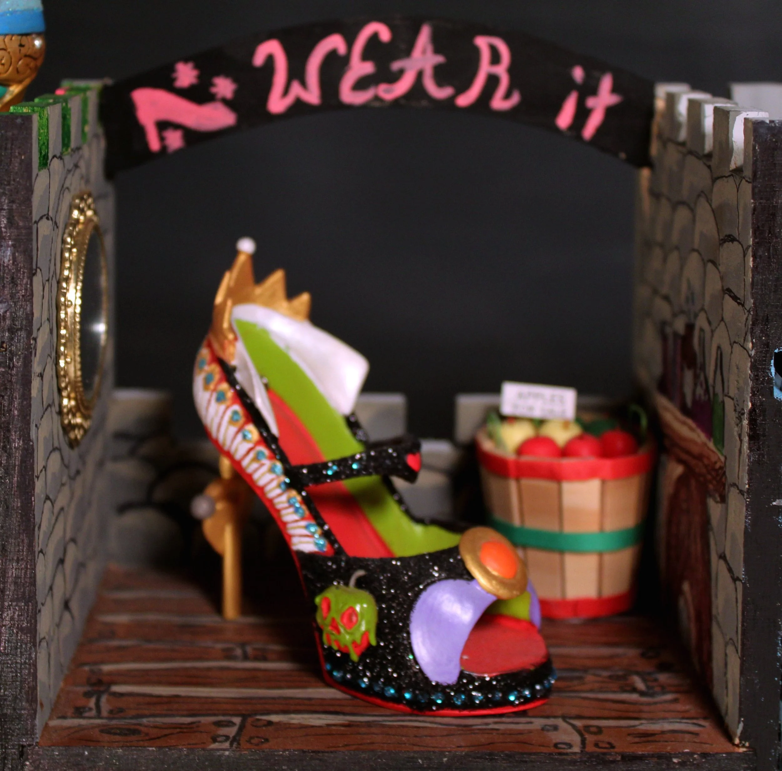 Decorative Halloween-themed display featuring a black arch with pink 'Wear it' text, skeletons, a skull decorative element, and Halloween accessories such as a witch's hat and pumpkins.