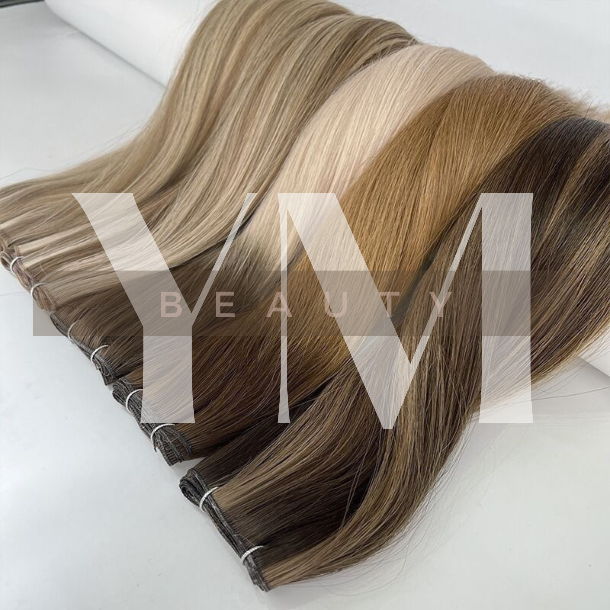 Samples of hair extensions in various shades of blonde and brown, arranged in a fan shape on a white background.