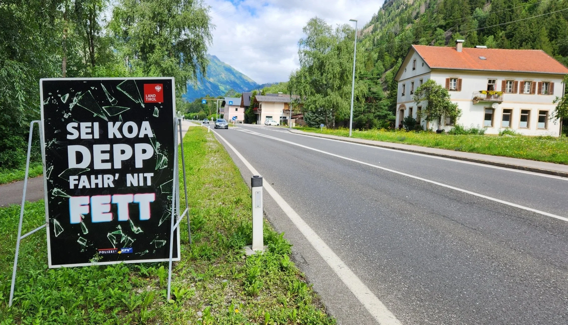 Plakat "Sei koa Depp, fahr nit Fett", neben einer Bundesstraße in Tirol