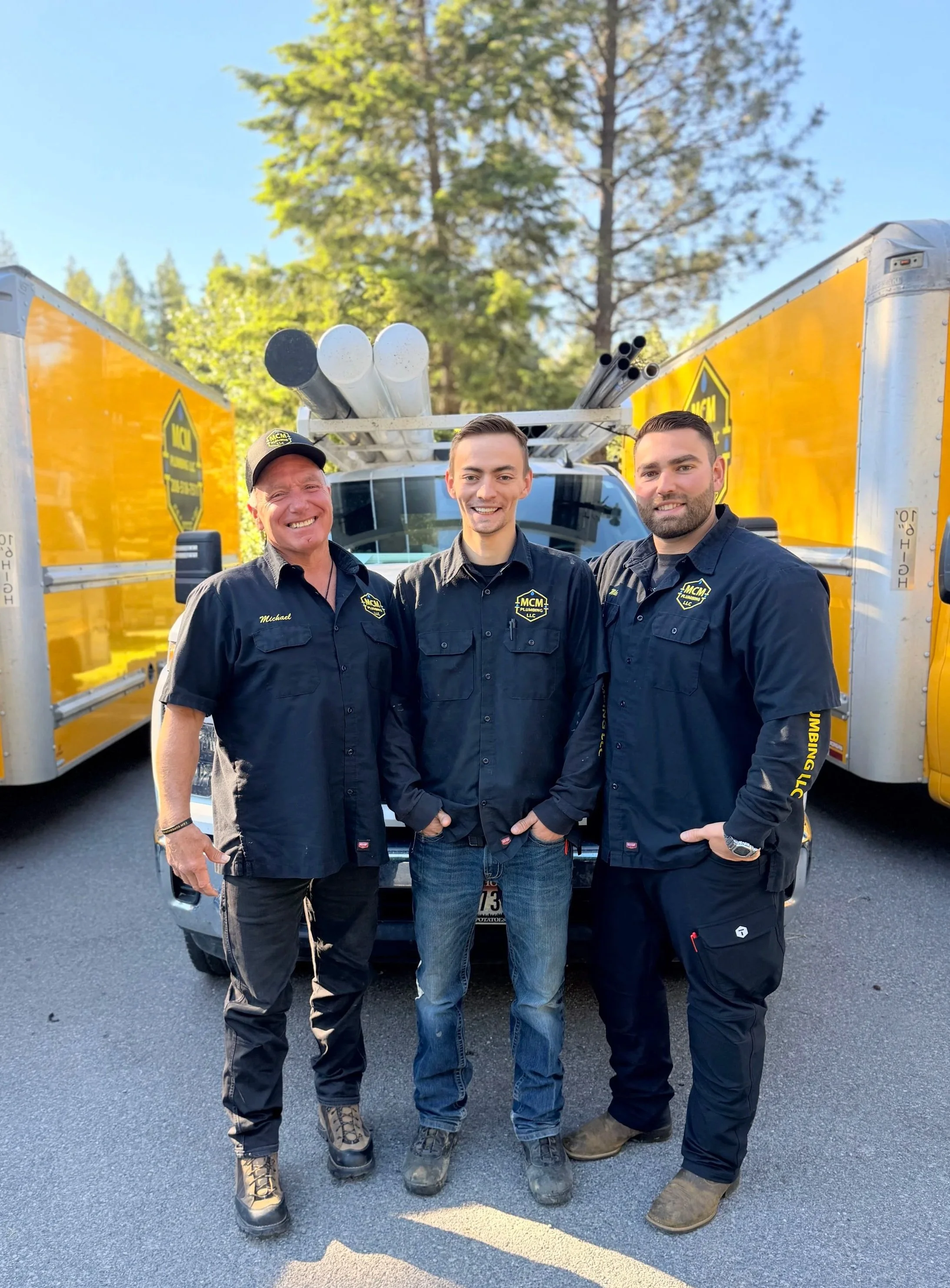 The MCM Plumbing LLC team standing in front of their vehicles.