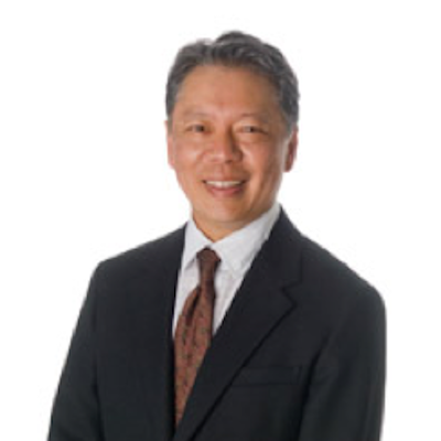 Portrait of an Asian man in a dark suit and tie, smiling against a white background.