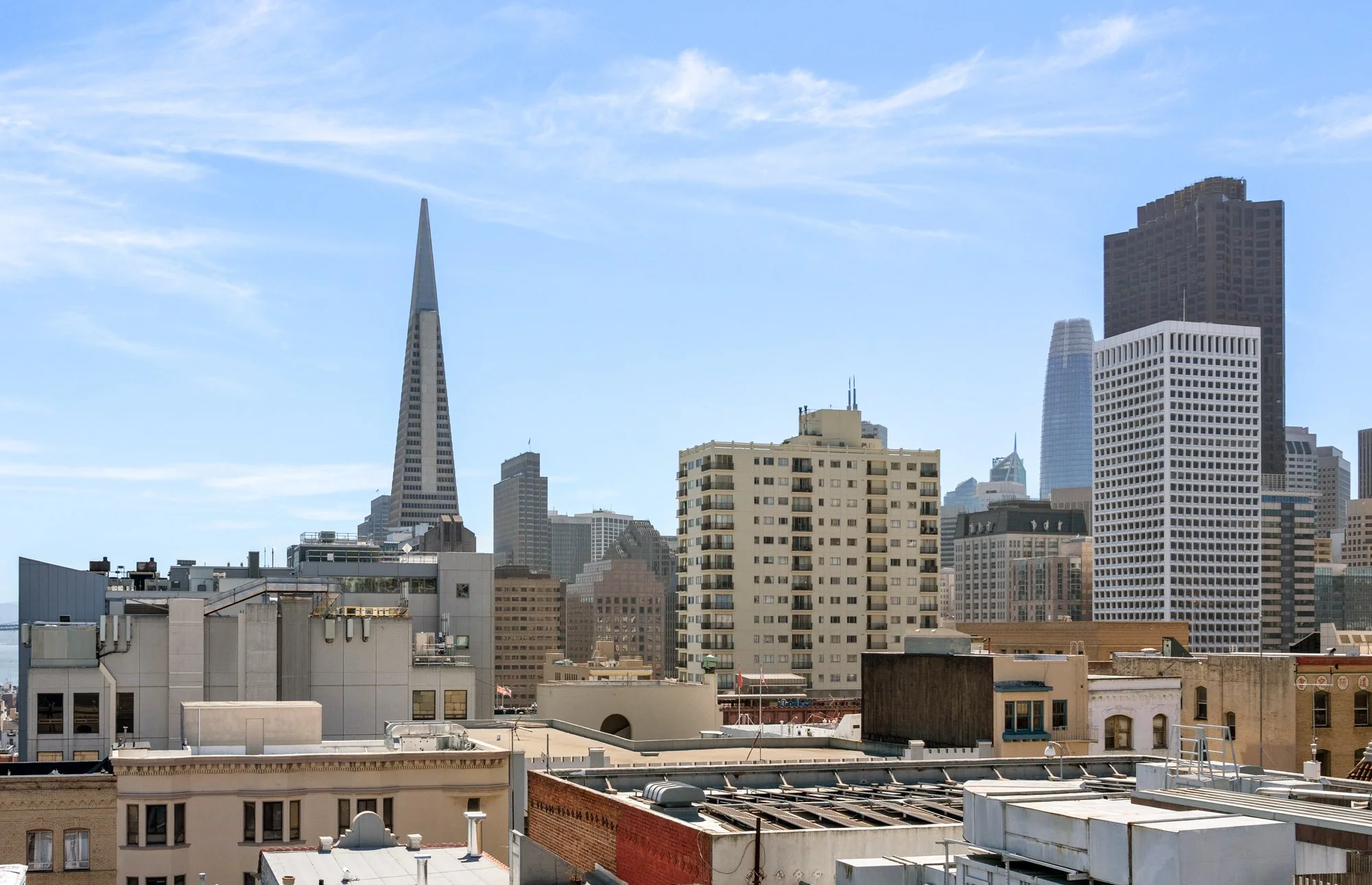 City skyline with tall modern skyscrapers, including the Salesforce Tower, under a partly cloudy blue sky.