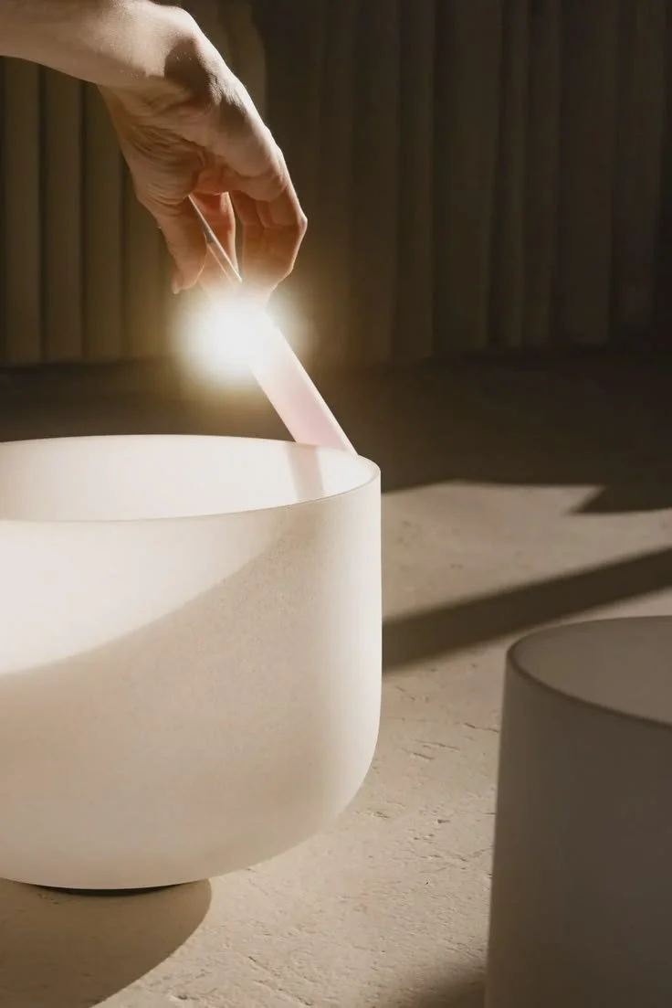 A hand inserting a white stick into a white bowl with sunlight and shadows creating a minimalistic scene.