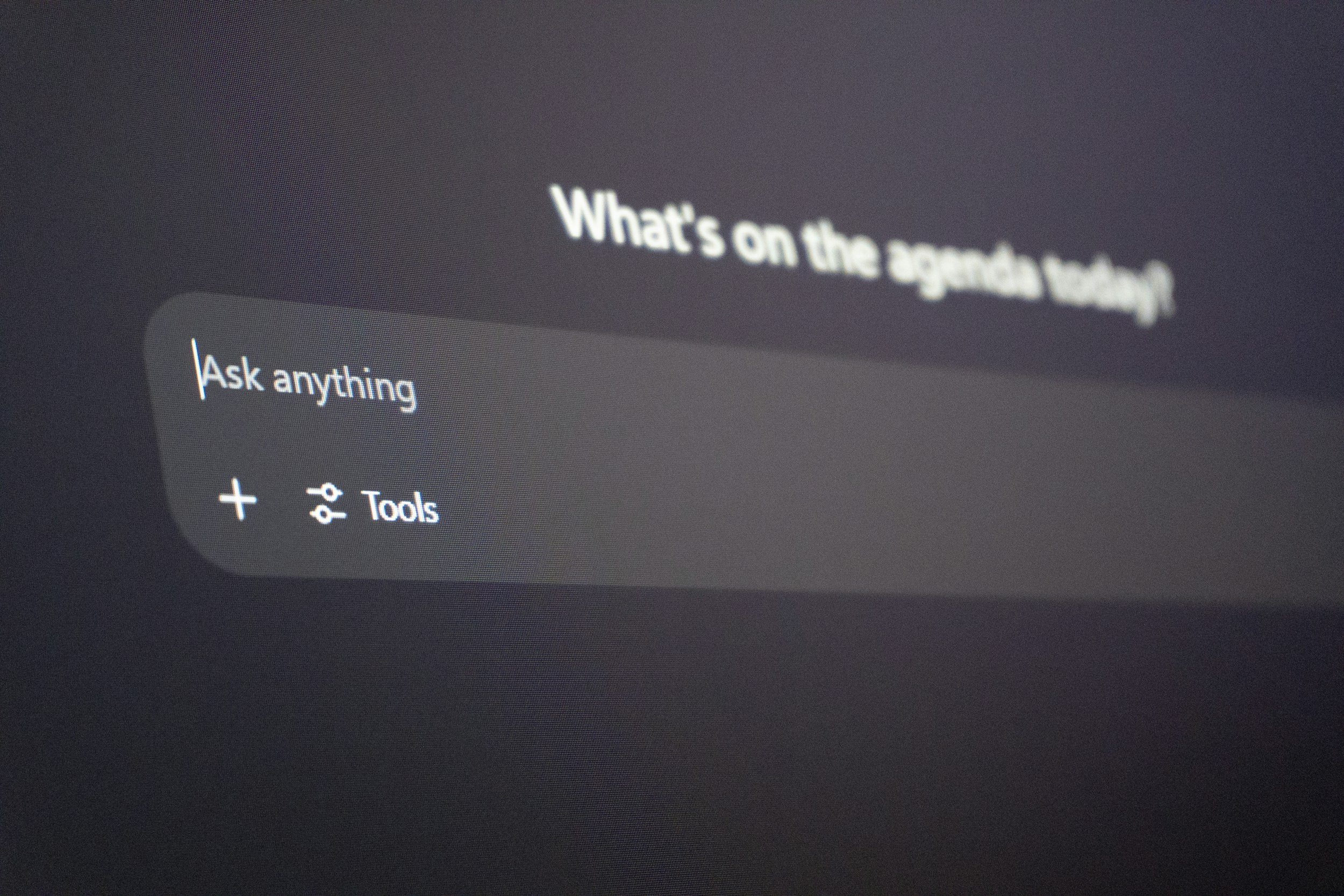 Close-up of a computer screen showing a search bar with the text 'Ask anything' and a prompt 'What's on the agenda today' displayed in the background.