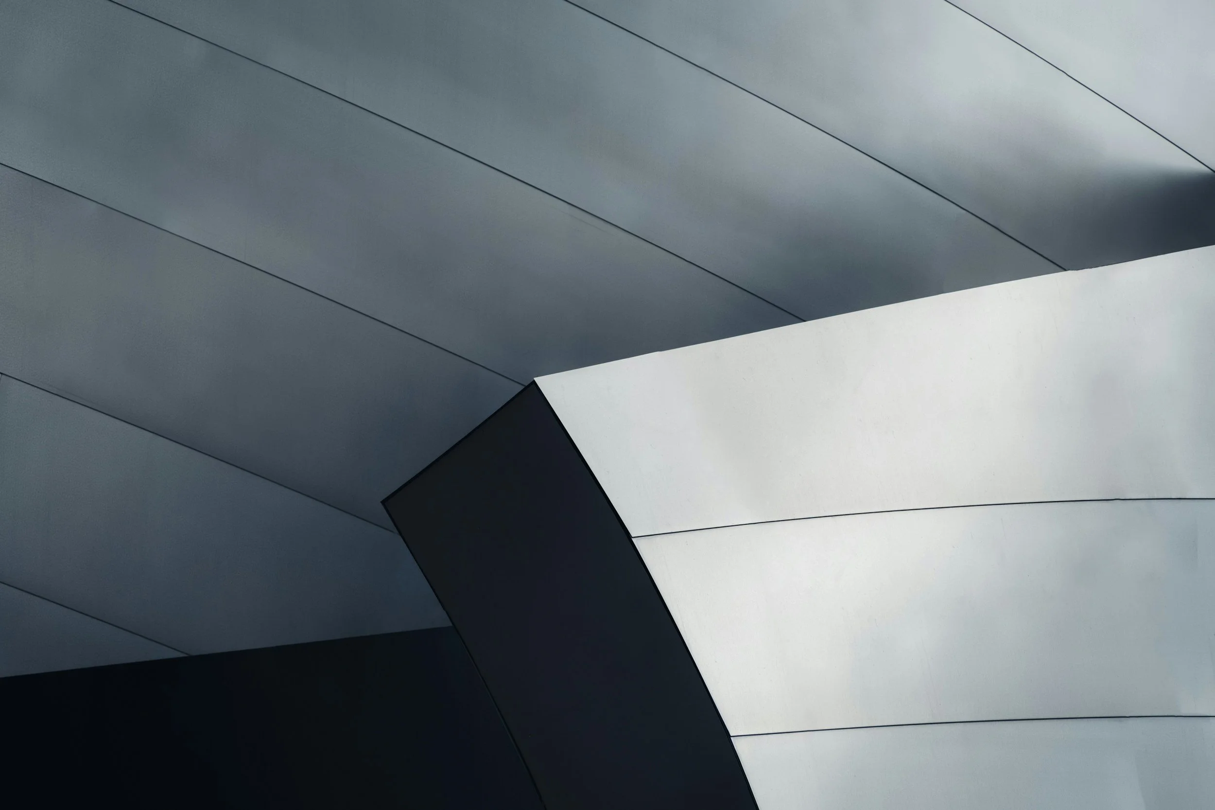 Close-up photograph of an architectural structure featuring sleek, curved metallic panels with a modern, minimalist design.