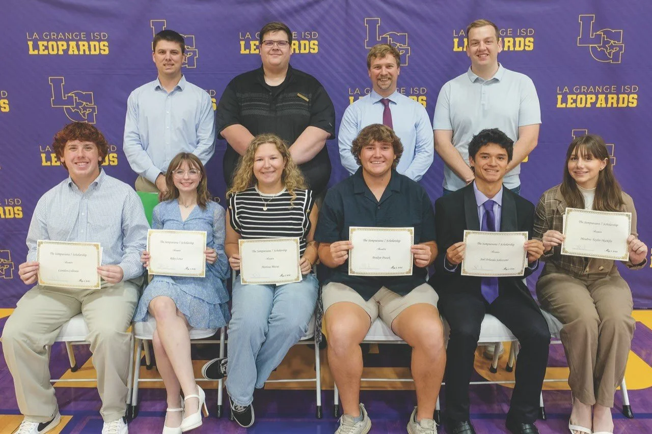 Group of nine students and two adults posing in front of a purple and gold La Grange ISD Leopards backdrop. The students are holding certificates, smiling, and are seated and standing in two rows.