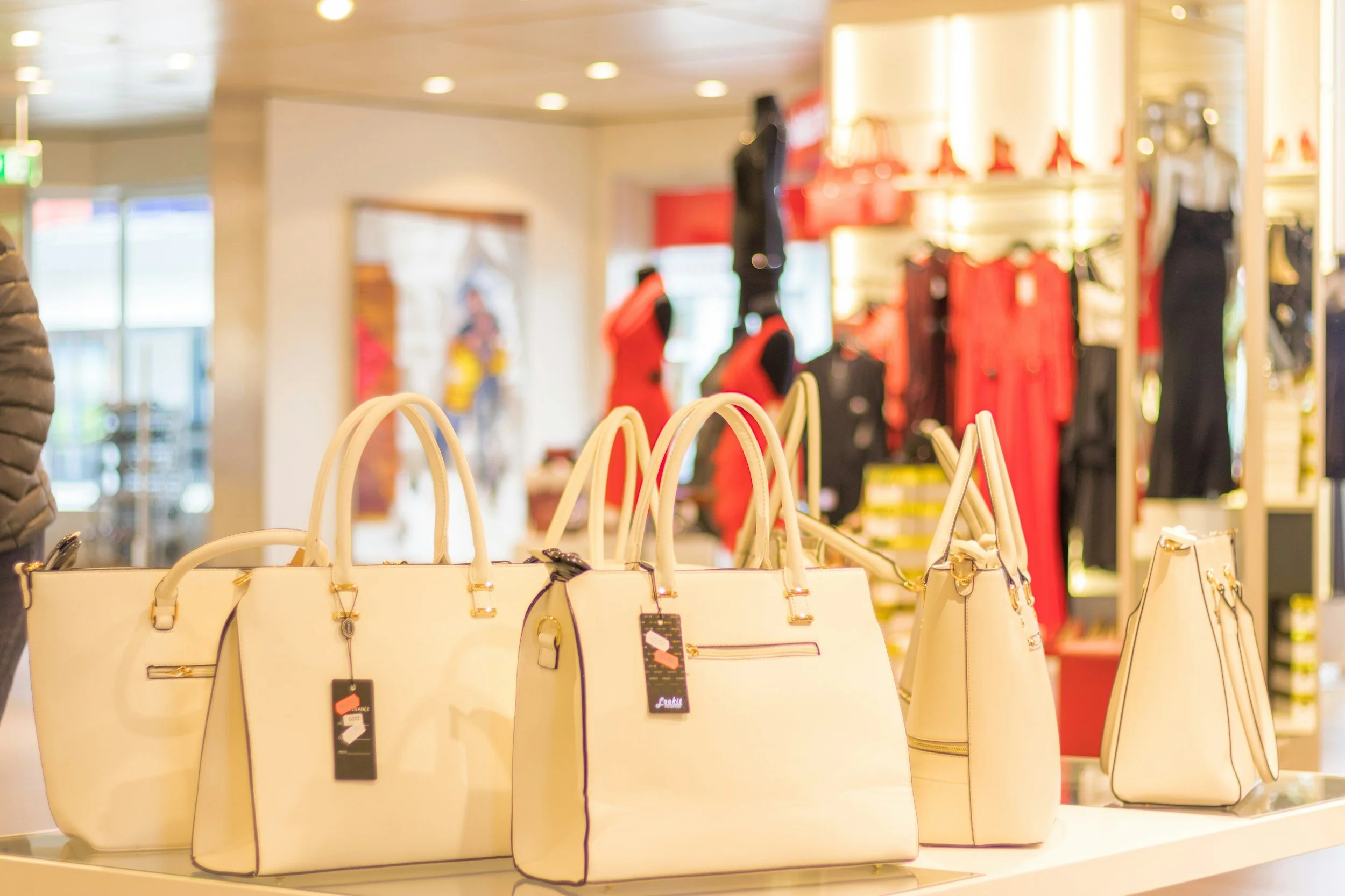 Display of white handbags with gold accents in a jewelry or handbag store