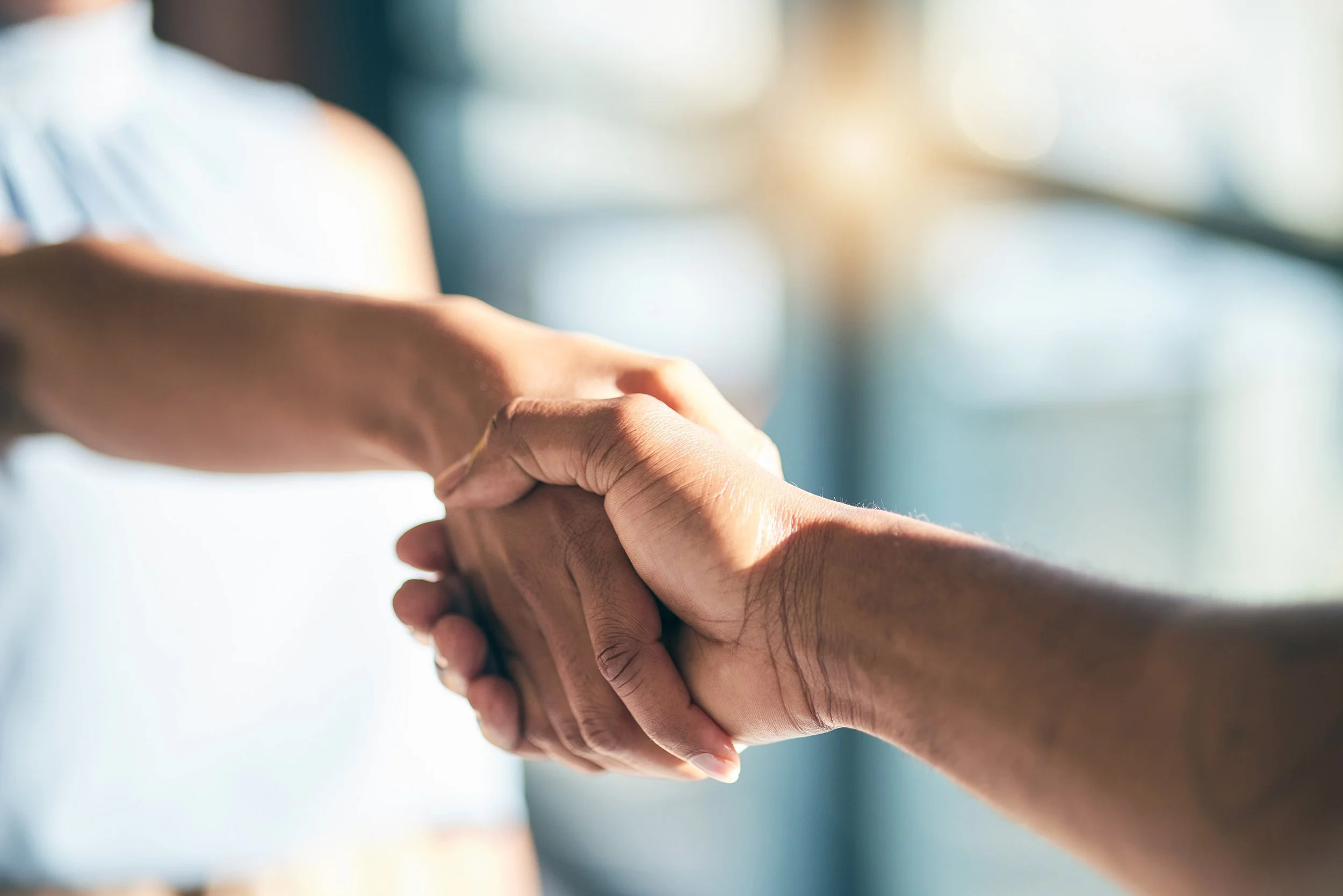 Close-up of two people shaking hands in a well-lit environment.