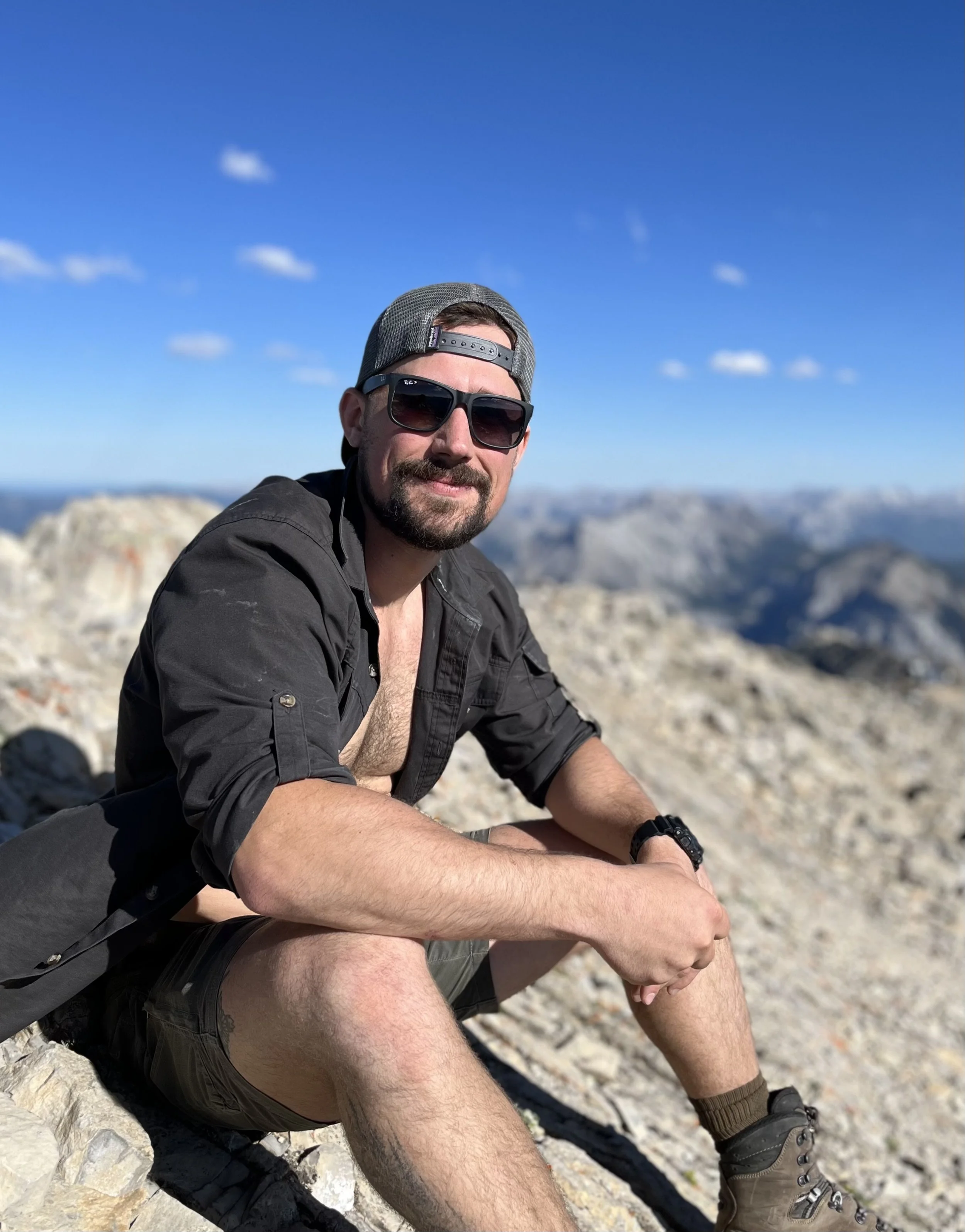 Contemporary Canadian landscape artist Kyle Boggild sitting on the summit of a peak in the Canadian Rockies.