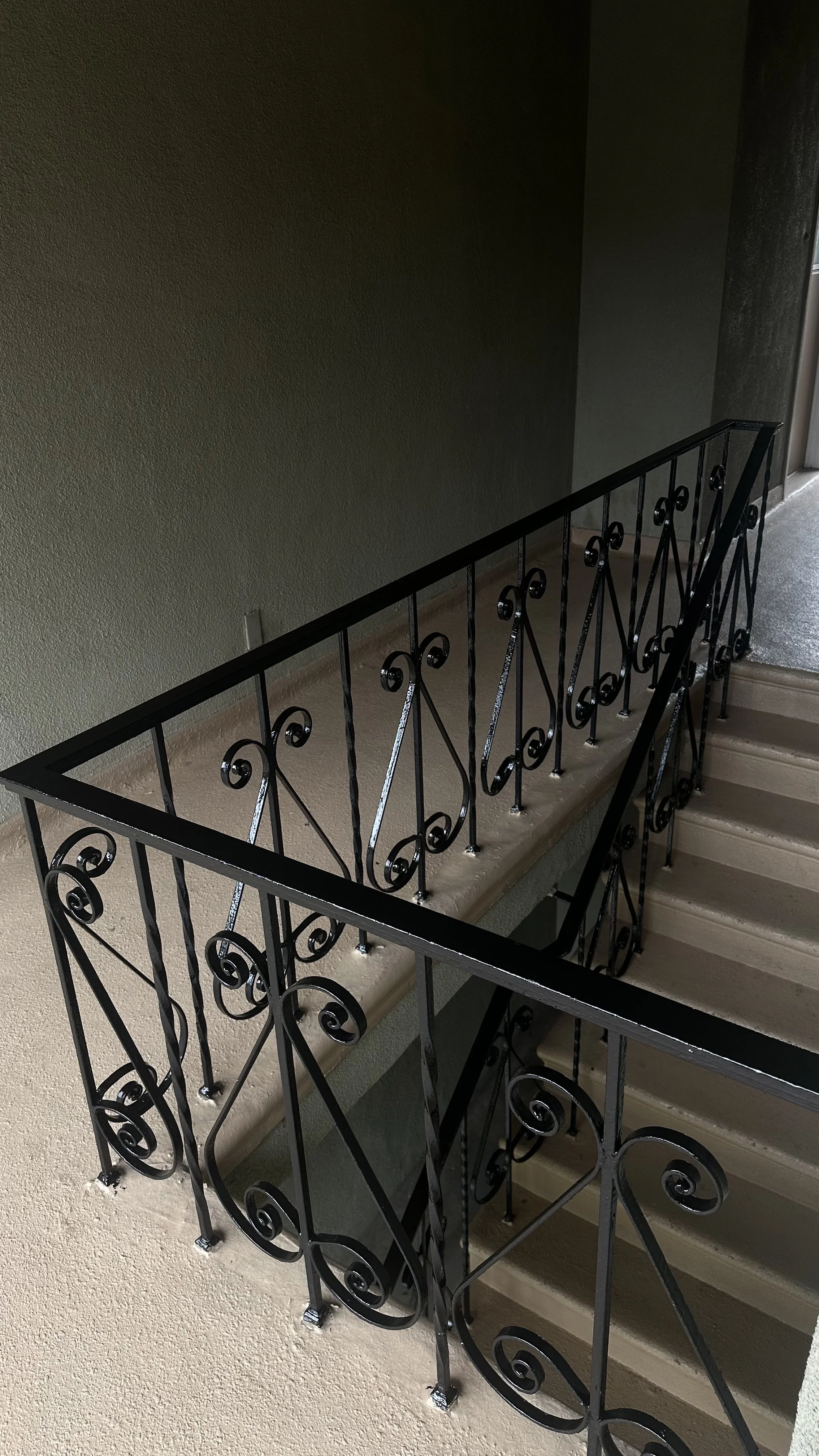 Barandal de hierro forjado negro en una escalera de interior en un edificio.