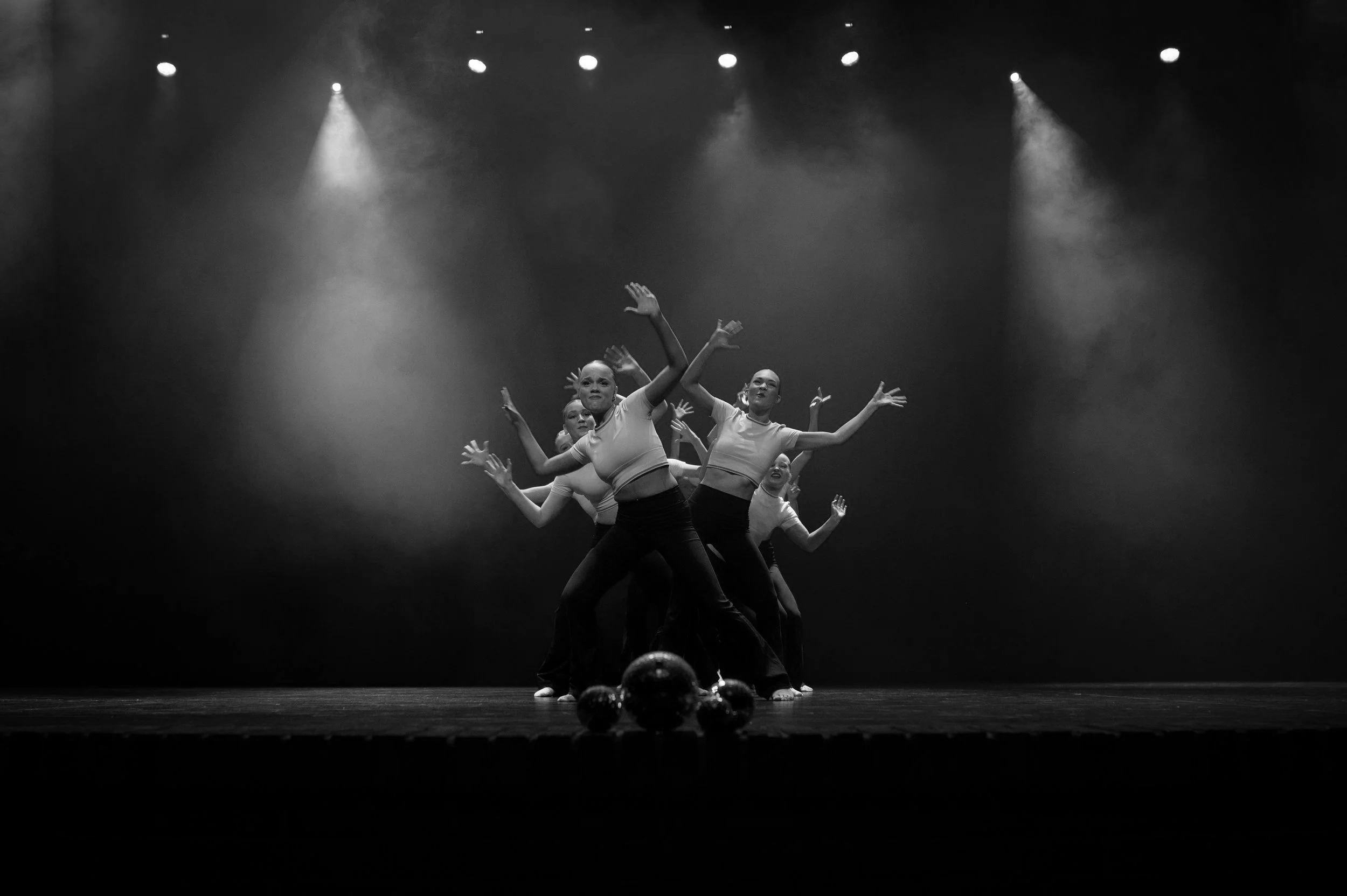Bilde av en gruppe dansere på scenen, i svart-hvitt, med spor av scenelys.