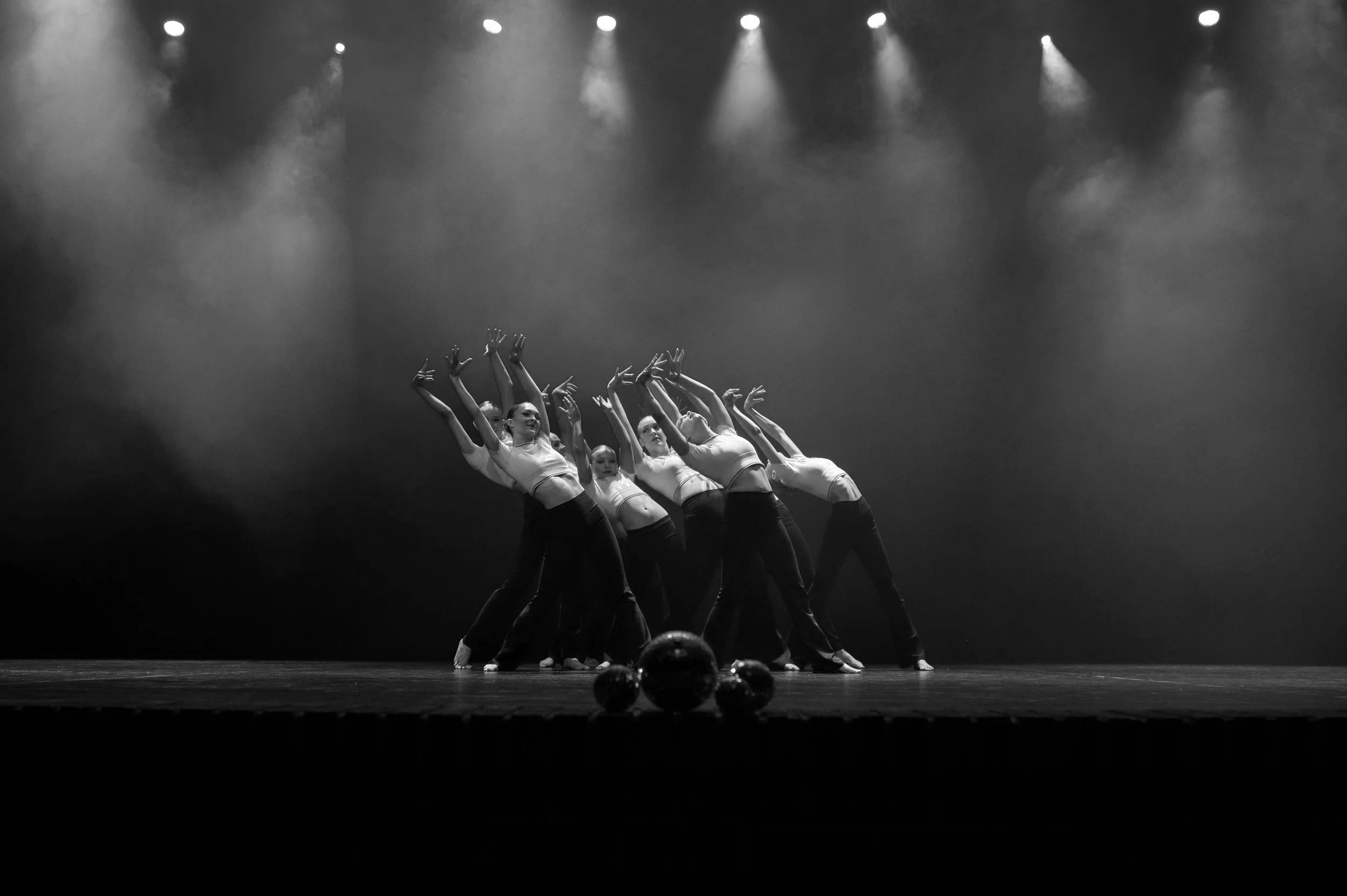 Gruppe dansere på scenen under en oppvisning, med scenelys og tåke.