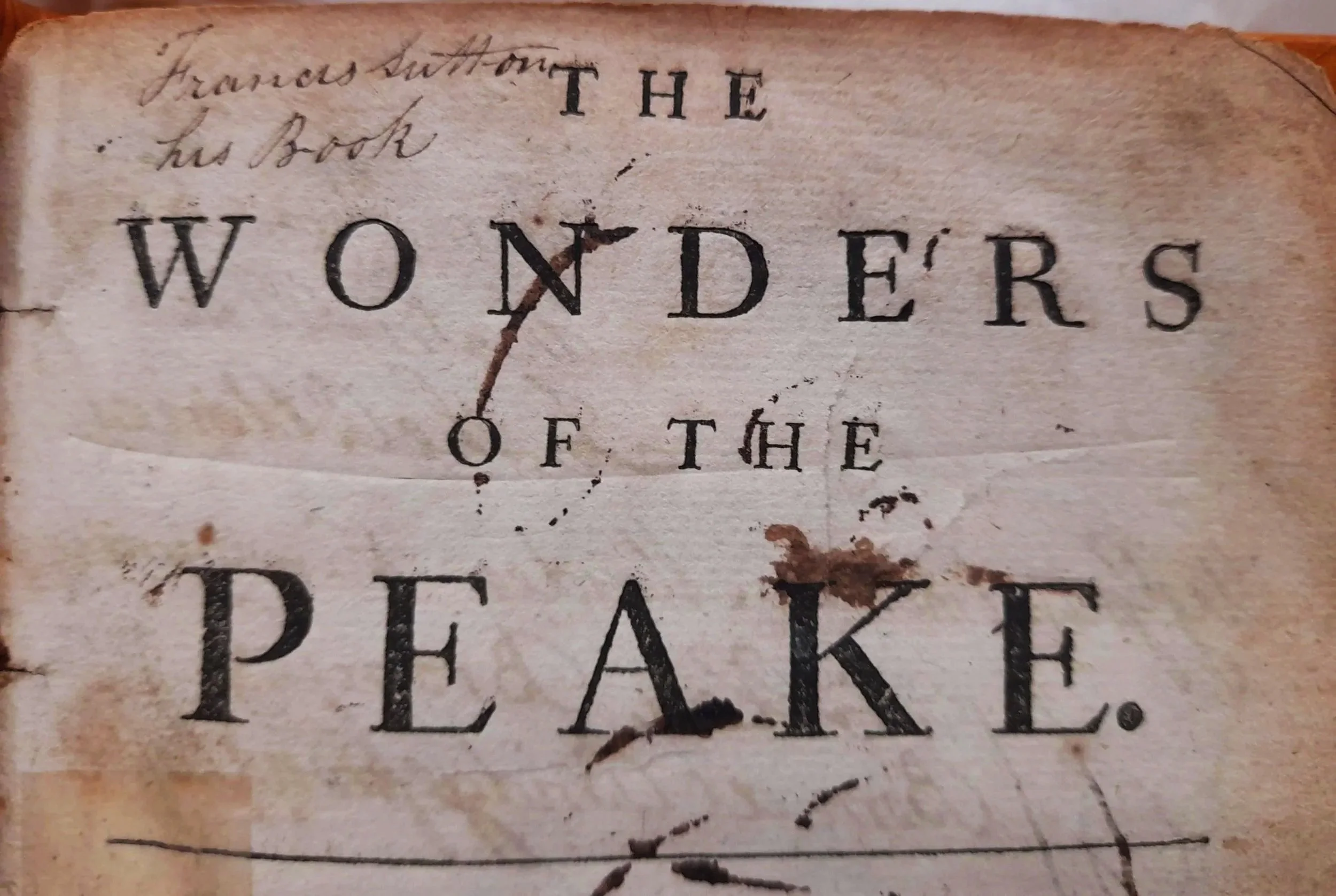 Close-up of an old, worn book page with handwritten and printed text, including the words "THE" and "WONDERS."