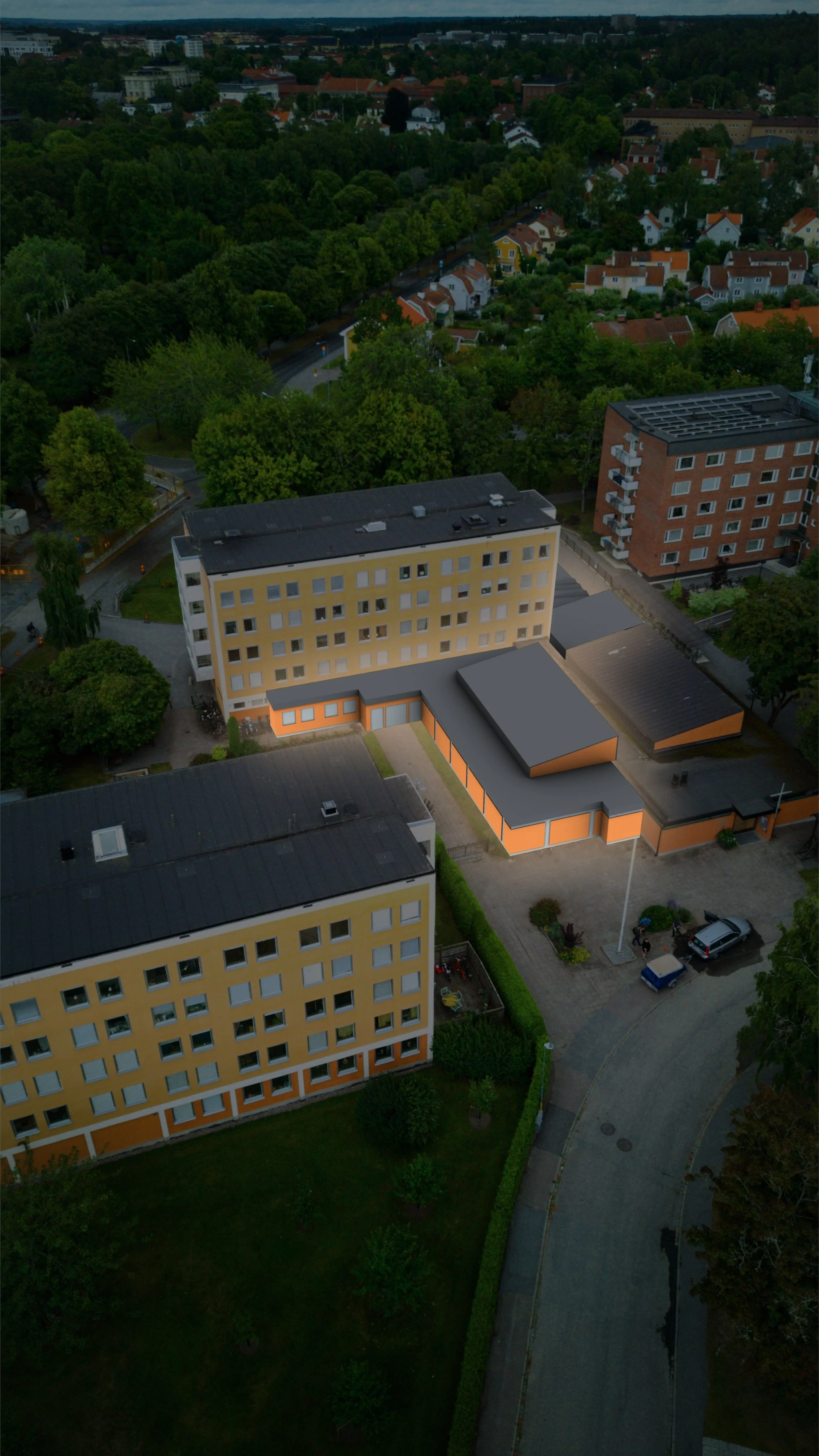 Flygbild av en stadsdel med gröna träd och olika byggnader, inklusive ett gult och ett orange bostadshus.