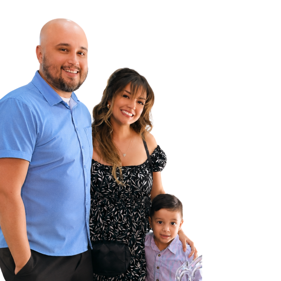 A smiling man with a beard in a blue shirt, a smiling woman with long hair in a black patterned dress, and a young boy with short dark hair in a striped shirt standing together for a photo.